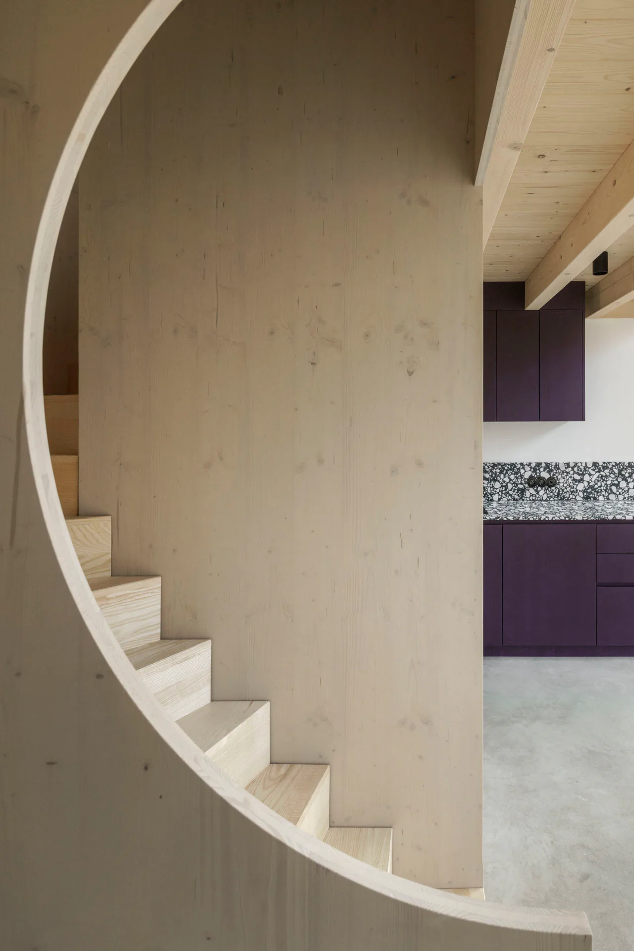 Eine Holztreppe erstreckt sich über die jeweils doppelgeschossigen Wohnbereiche.