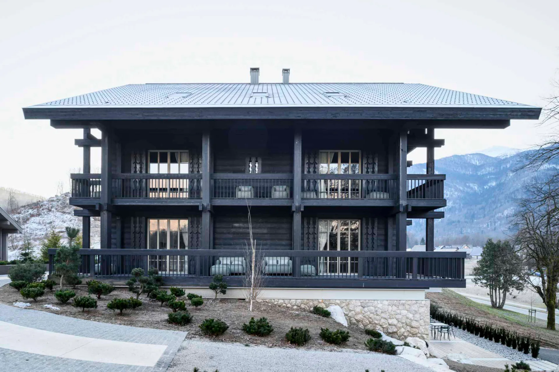 Die Villa Muhr steht auf einem Hanggrundstück am Ortseingang von Ribčev Laz. Von der Talseite aus ist die Gliederung des Gebäudes in einen Sockel aus Stein und einen Aufbau aus Holz gut zu erkennen.