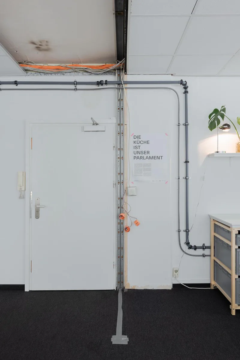 Offen an der Wand liegende Rohre, welche an die Zu- und Abwasserleitungen des kleinen vorhandenen Büro-Badezimmers angeschlossen wurden, versorgen die Küchenzeile mit Wasser.