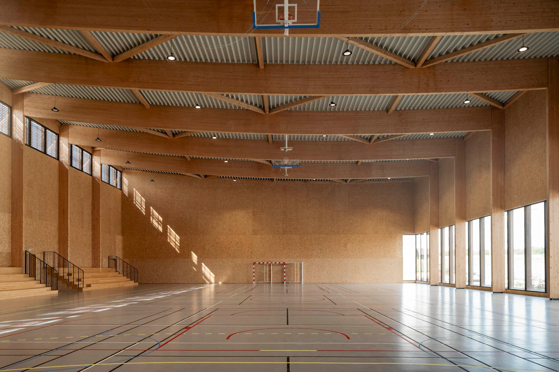 Eindrucksvolle, konkav gekrümmte Leimholzbinder tragen das Dach der Sporthalle.