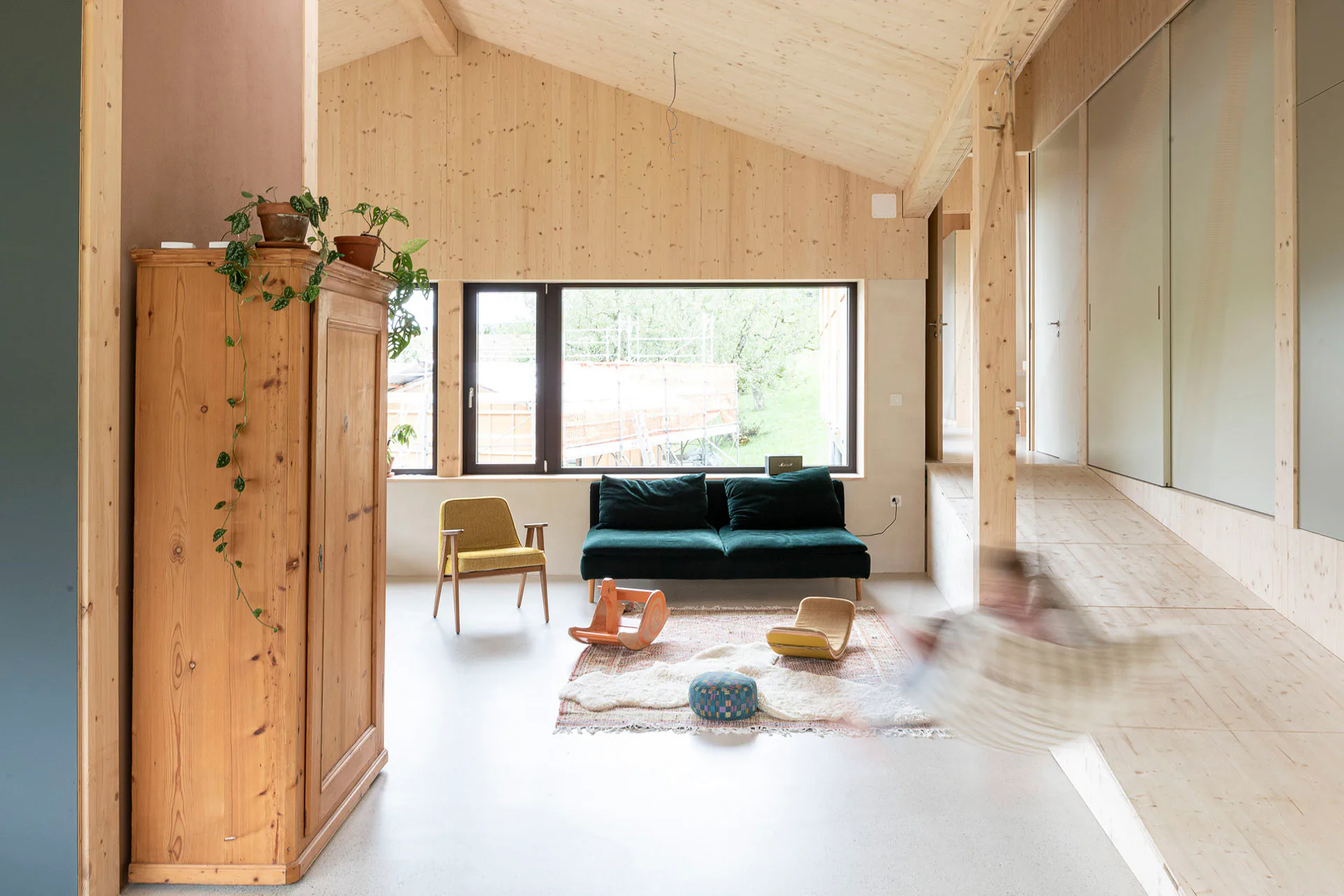 Eine flache Rampe aus Holz führt vom Eingangsbereich hinunter in den Wohnraum.