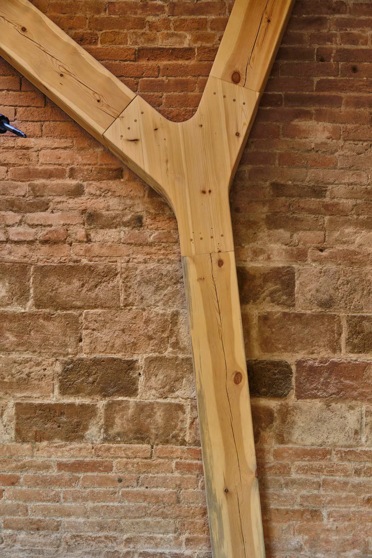 Holzstütze vor Ziegelwand.