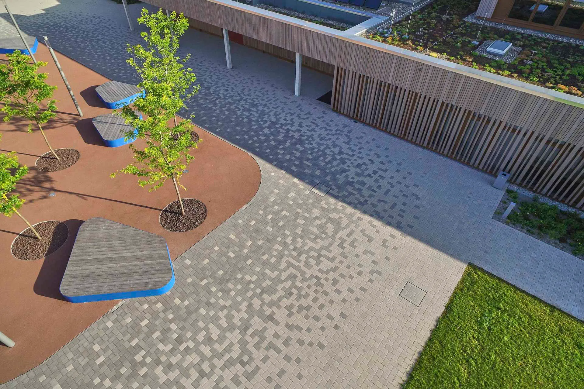 Rutschhemmende und wasserdurchlässige Steine mit Blindenleitsystem sichern Schulhof und Parkplatz und reduzieren Aufheizung.