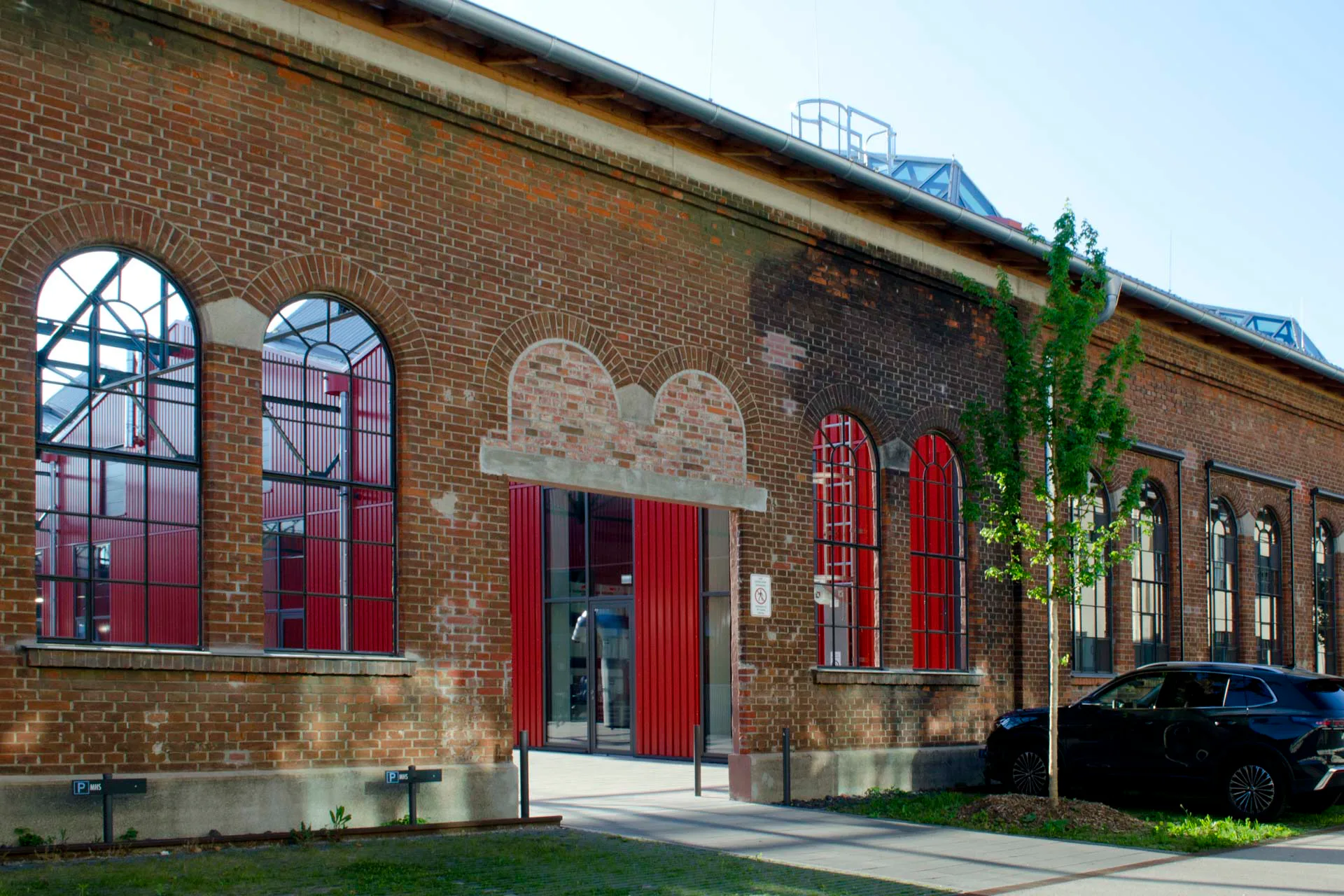 Das stählerne Dachtragwerk vermittelt das Prinzip einer Gesamthalle, den äußeren Rahmen gibt das umlaufende Bestandsmauerwerk – hier am Hofeingang Südwest – vor.