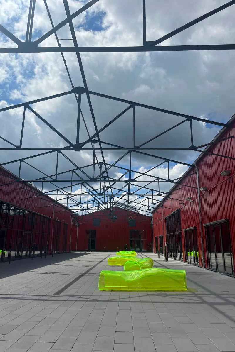 Stahlfassaden in kräftigem Rot fassen die neu entstandenen Höfe, leuchtend gelb fluoreszierende Kunstobjekte aus Plexiglas laden zum Verweilen ein.