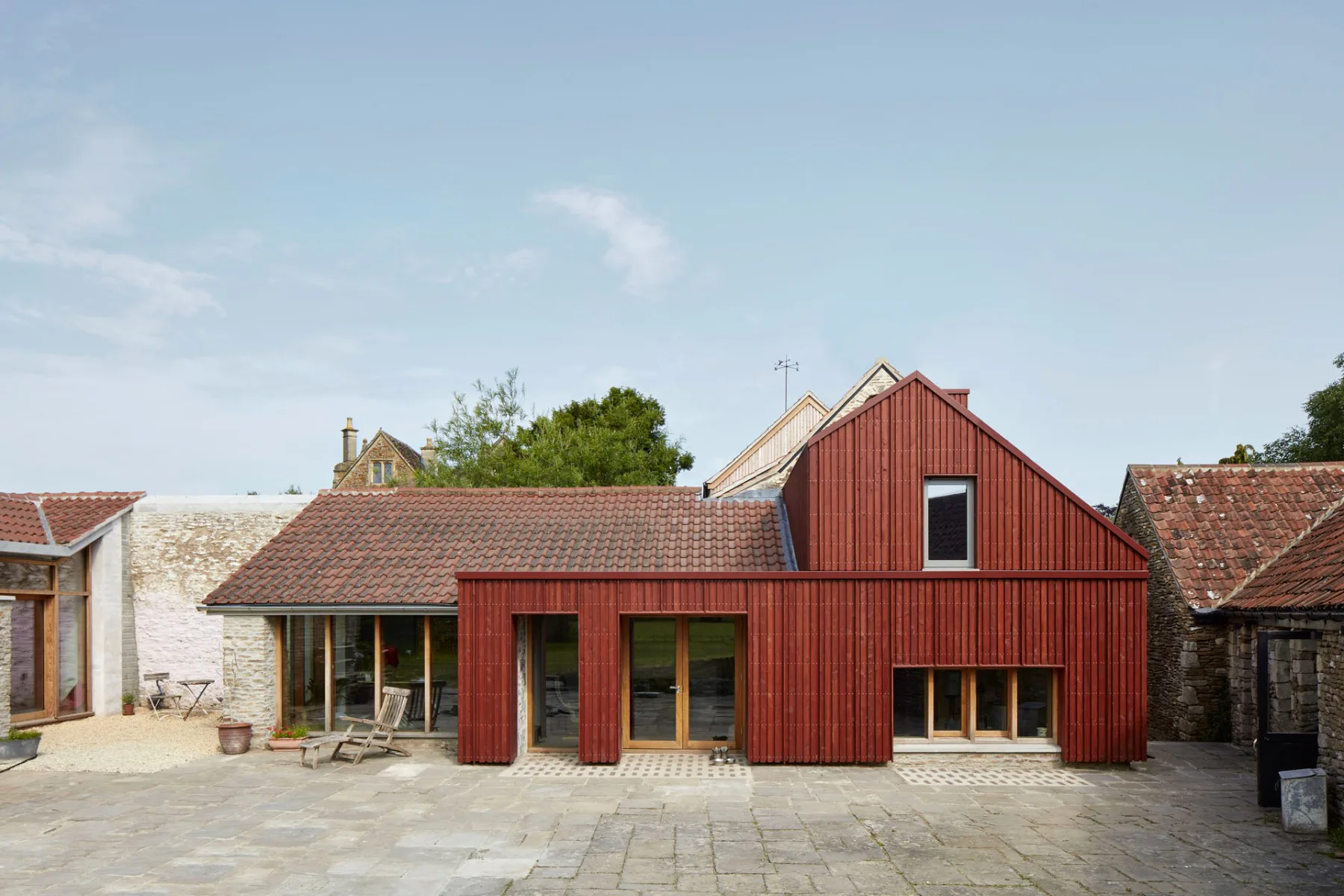 Der bestehende Anbau wurde mit rot lasiertem Holz neu verkleidet.