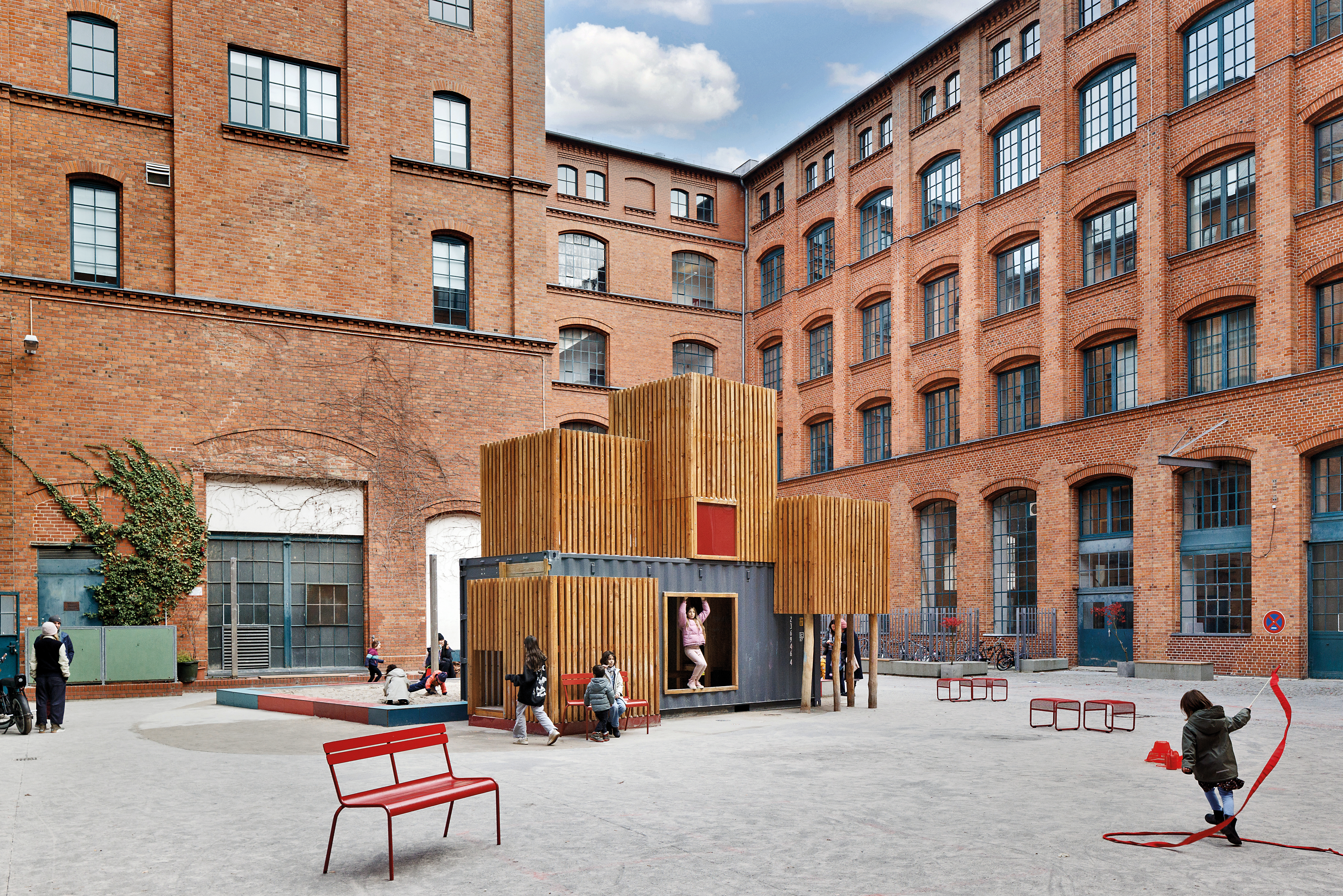 Für den Schulhof im denkmalgeschützten Ensemble des Berliner Phorms-Campus (2023) hat Baukind eine vertikale Containerlandschaft gestaltet: kompakt, aber mit viel Spielraum.