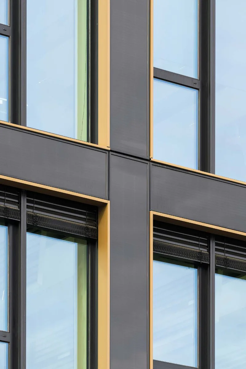 Die bronzefarbenen Einfassungen der Fenster bilden einen dezenten Kontrast zum annähernd schwarzen Farbton der Fassadenelemente.