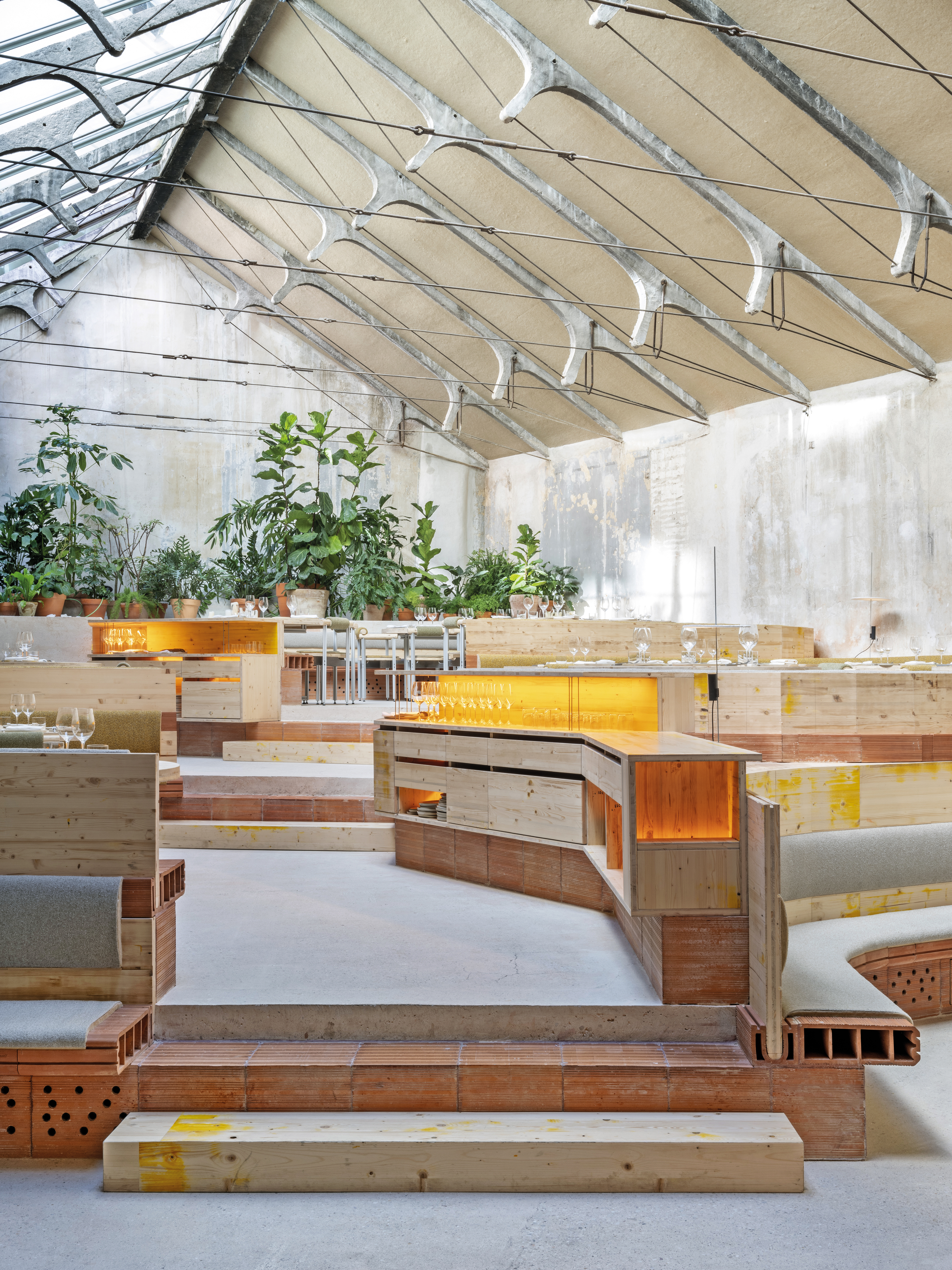 A continuous skylight allows the slender concrete beams of the original roof construction to radiate brilliantly. The backlit service furniture serves to prepare the tableware.