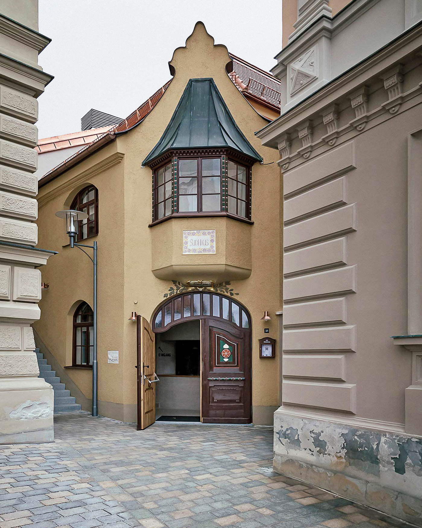 Vom ehemaligen Brauereigebäude steht nur noch der denkmalgeschützte Kopfbau. Das Rundbogenmotiv des Eingangs setzt sich als Zitat im Gastraum fort.