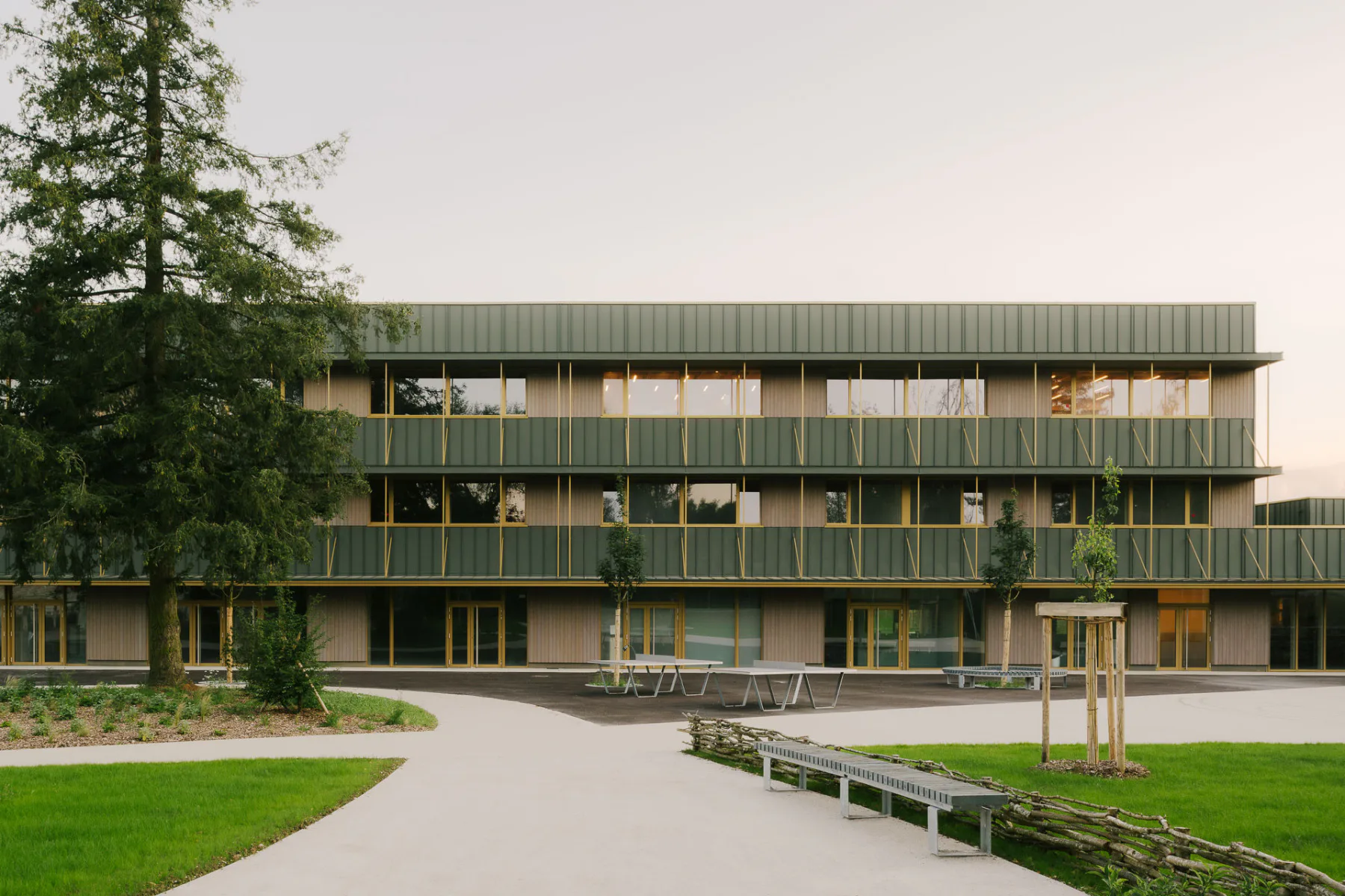 Das Collège Maryse Bastie stammt aus den 1970er-Jahren. Bei der Sanierung erhielt es eine neue, einheitliche Hülle aus grünem Stehfalzblech, grau lasierter Lärchenholzschalung und markanten gelben Fensterrahmen.