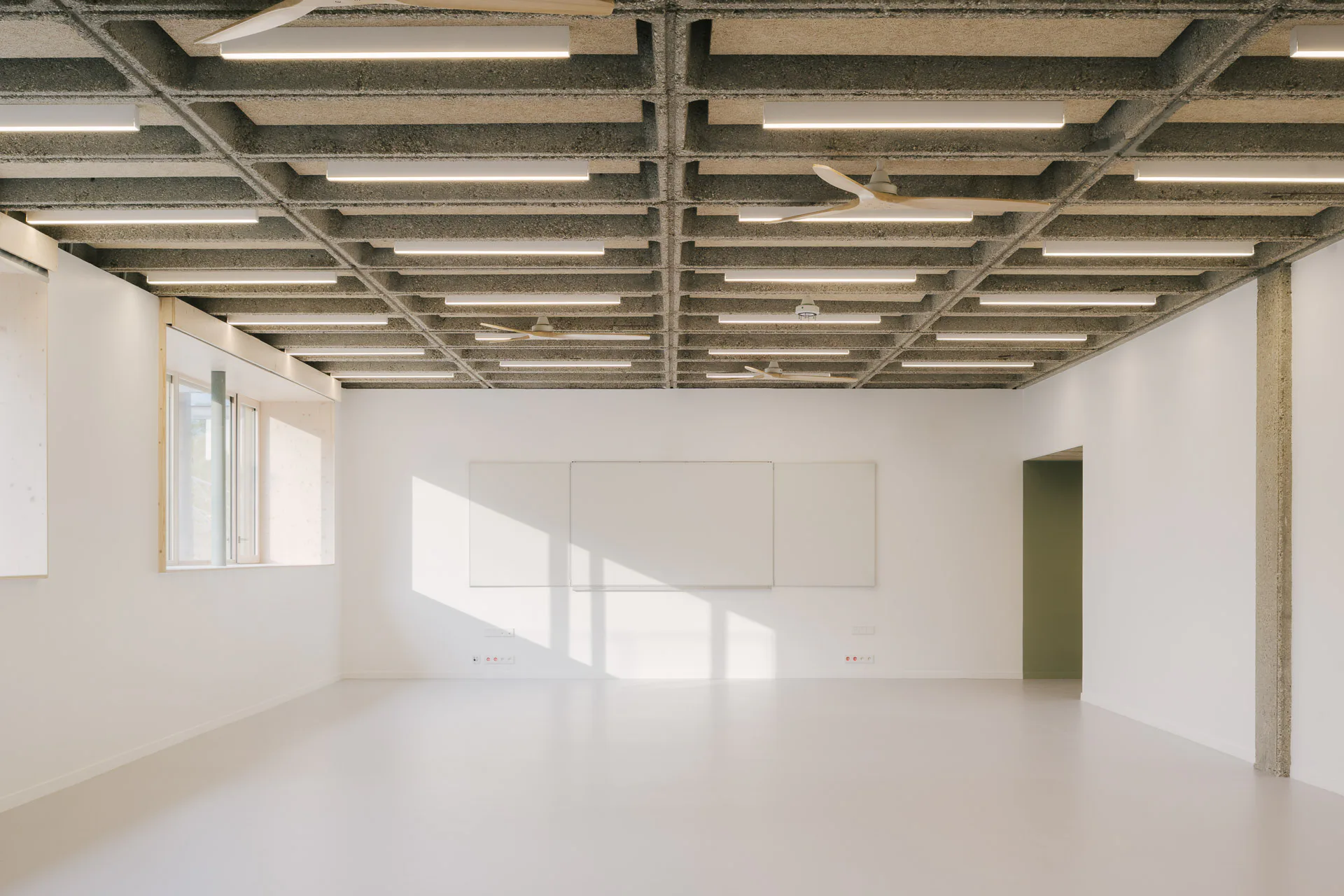 In den Bestandsgeschossen wurde die gerasterte Betondecke offen gelegt. Darin dämpfen eingelegte Holzwolle-Leichtbauplatten den Schall.