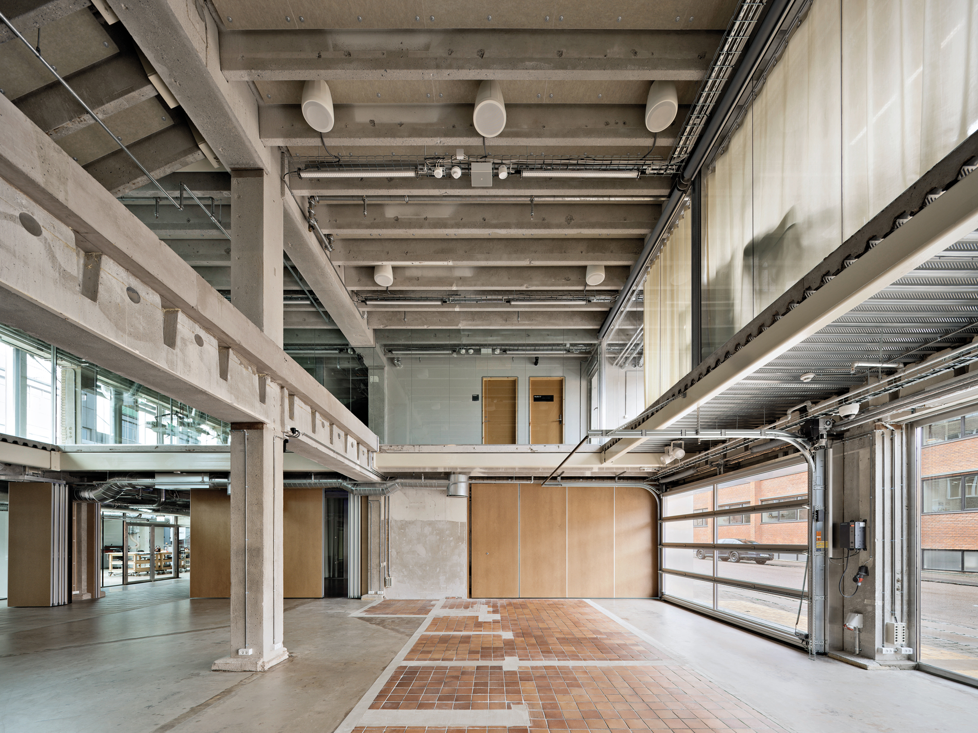 An einigen Stellen ist der ehemalige Grundriss im Bodenbelag ablesbar. Große, transparente Garagentore öffnen das Kulturzentrum zum Straßenraum.