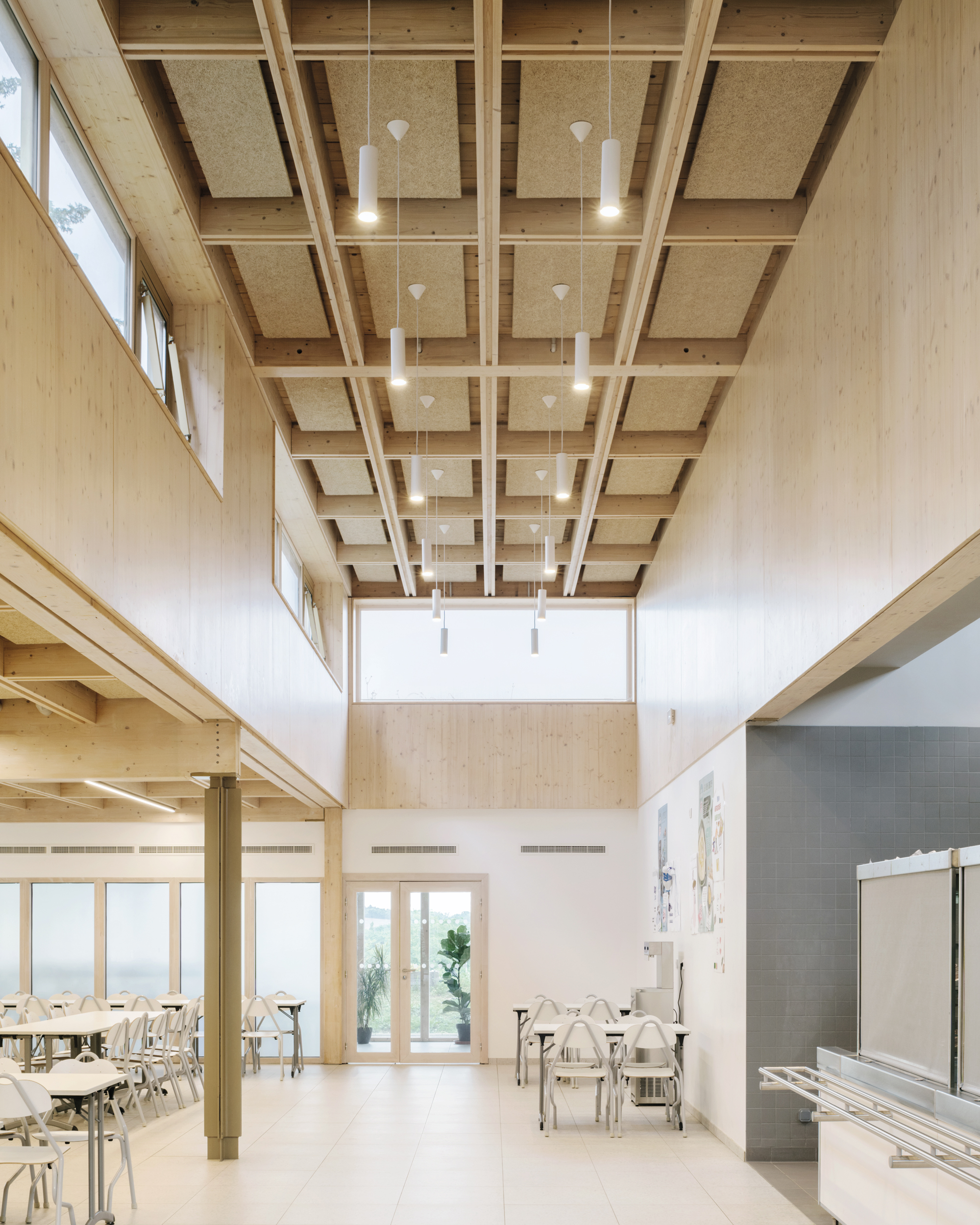 Die Mensa erhielt eine Rasterdecke aus Holz, die sich an die Betonstruktur des Bestands anlehnt.