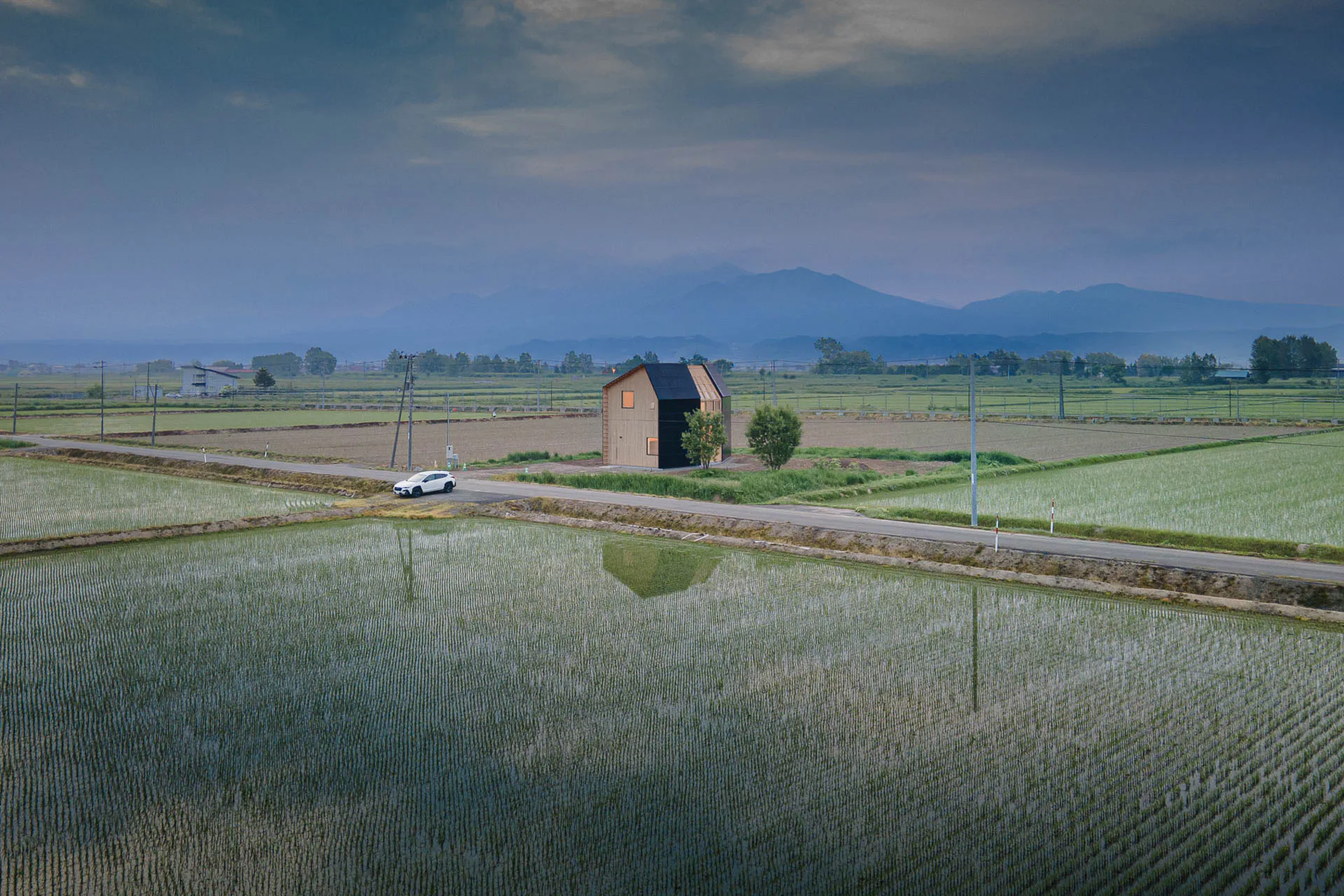 Das ländliche Umland bietet einen Panoramablick auf Ackerland, Infrastruktur und in die Ferne ragende Bergketten.