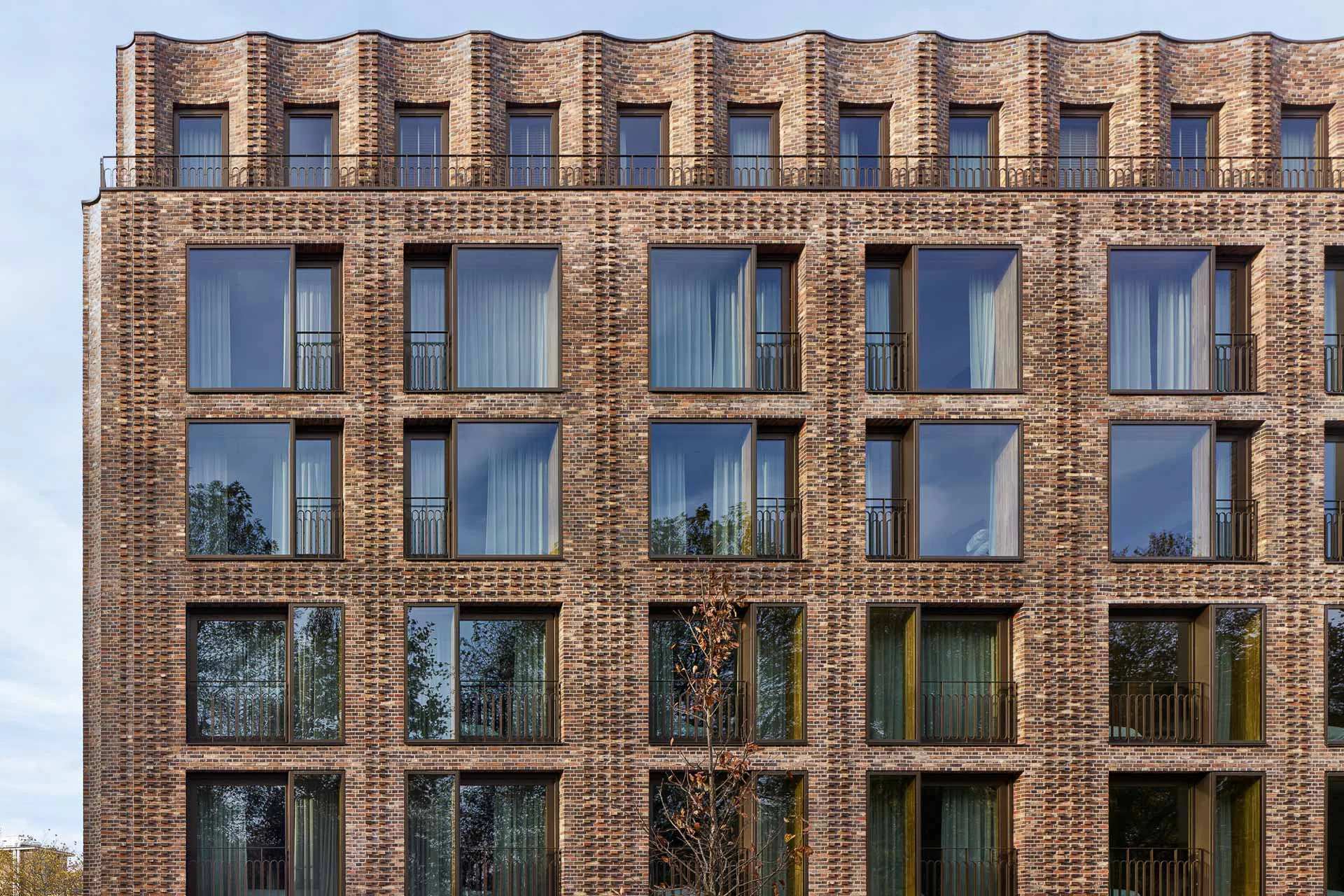 Das oberste Stockwerk ist leicht zurückgesetzt und bildet eine moderne Krone mit einer wellenförmigen Fassade.