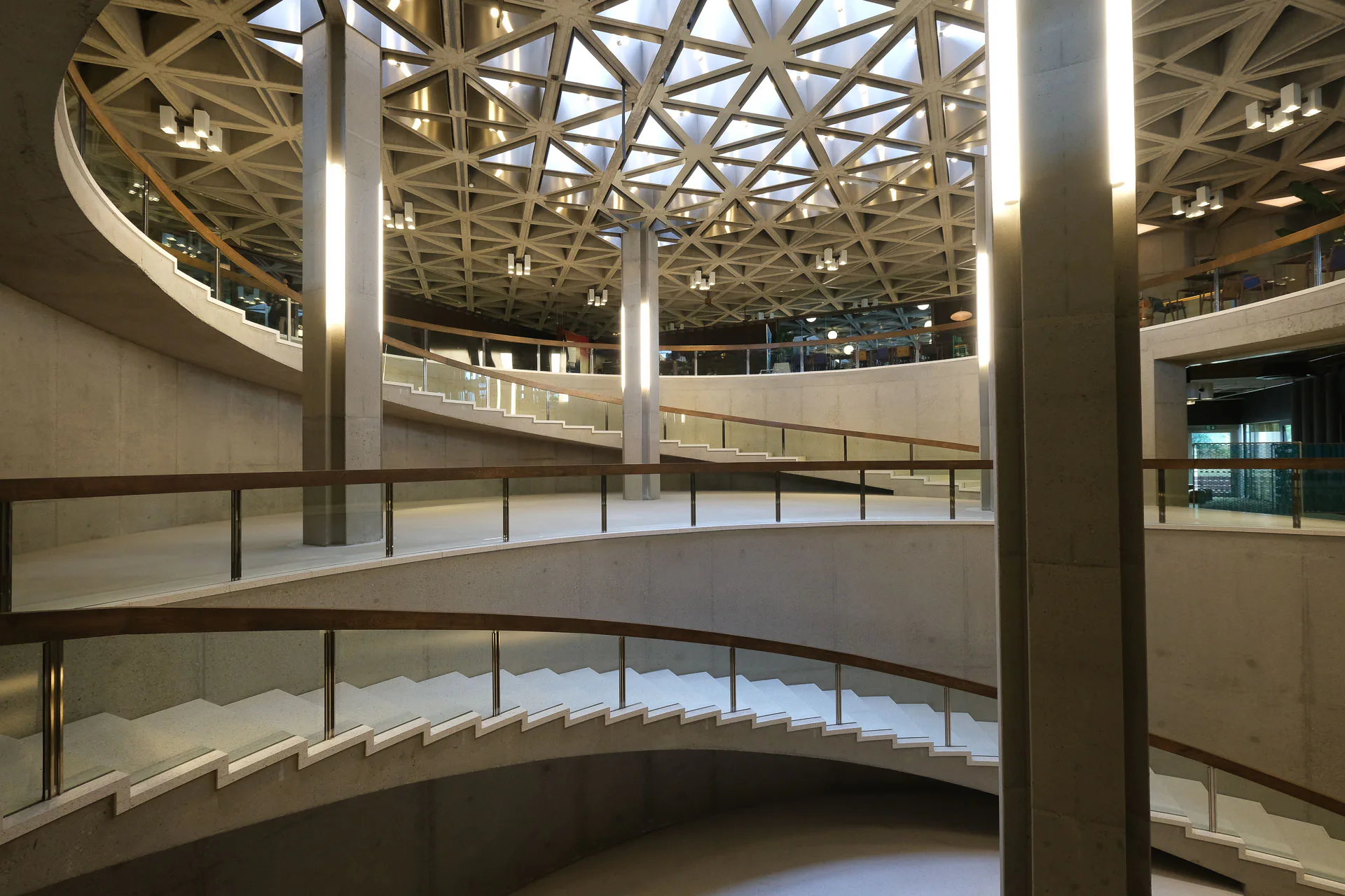 Das Atrium liegt an der Schnittstelle der beiden annähernd quadratischen Sockelbauten und verbindet alle Nutzungen in den unteren Geschossen miteinander.