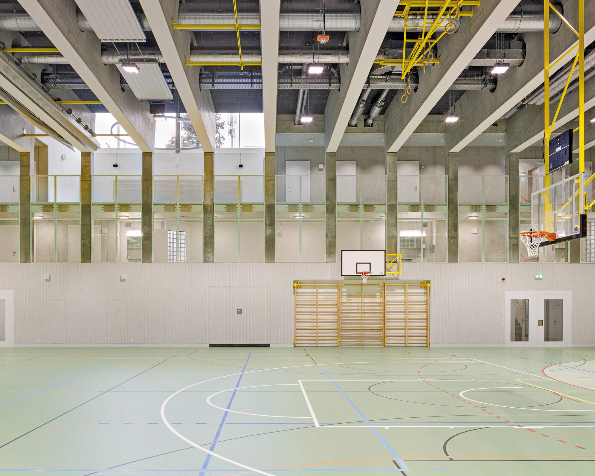Eine zweigeschossige Zuschauergalerie versorgt die unterirdische Sporthalle punktuell mit natürlichem Licht.