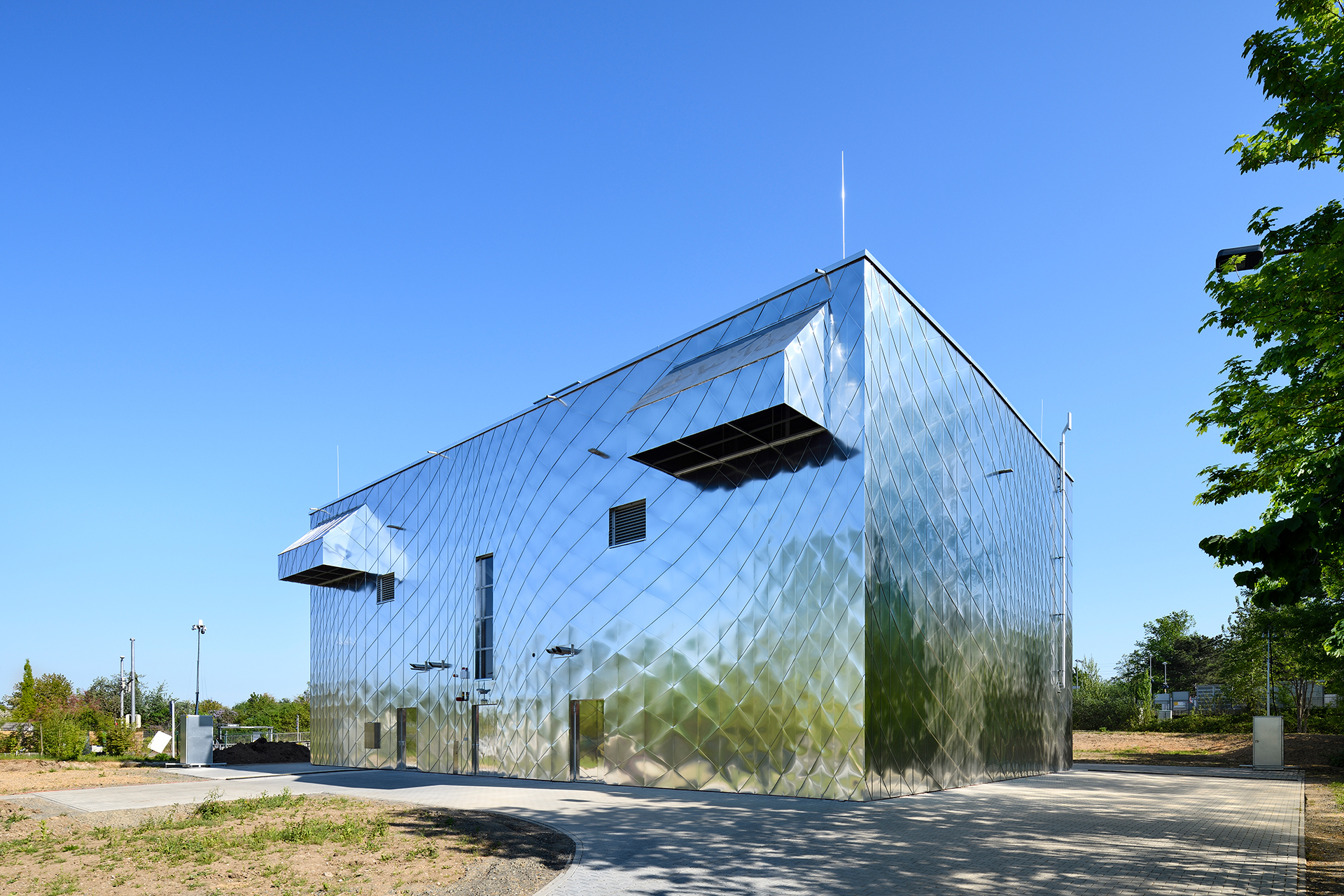 Die spektakuläre Fassade besticht mit hochglänzenden Aluminiumschindeln unterschiedlicher Form, die zu einem Wirbelmuster angeordnet wurden. Dadurch wird das Gebäude optisch aufgelöst und mit der Umgebung verschmolzen.