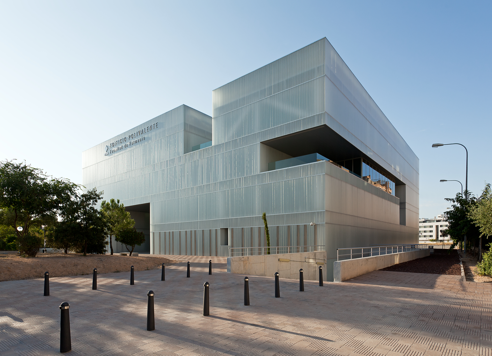 Auf dem Campus der Universität von Kastilien-La Mancha in Albacete steht das Edificio Polivalente, Mehrzweckbau der Pharmaziefakultät. Rund 60 Studierende nutzen den neun Millionen Euro teuren Bau mit 9 200 m² für Klassenräume, Büros, Kommunikations- und Werkstatträume. Der prismatische Bau aus sandgestrahltem LINIT EcoGlass mit quadratischer Grundfläche fällt neben seiner transluzenten Erscheinung auch durch große rechteckige Ausschnitte auf allen vier Seiten auf.