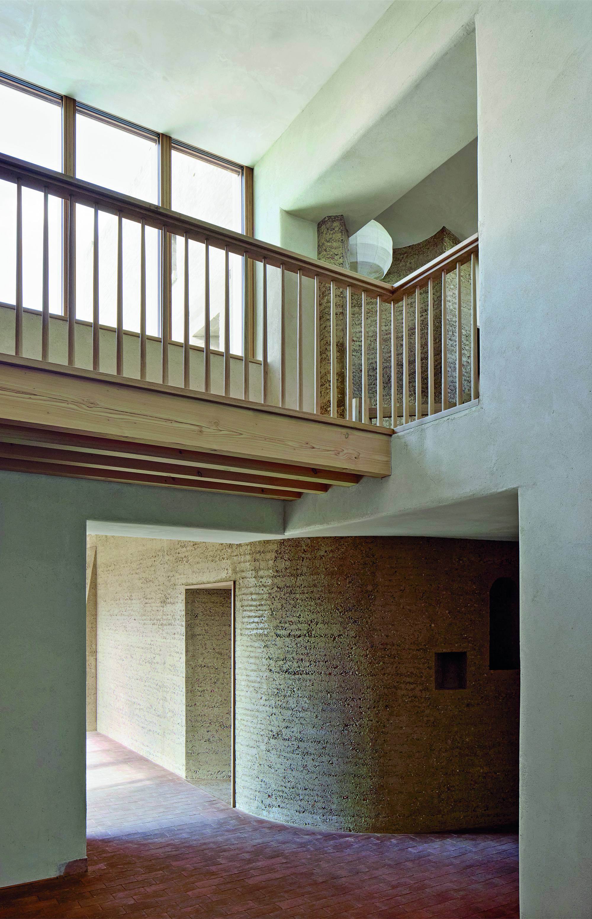 The residential house is structured into different volumes. The hallway offers a glance of the upper floor.