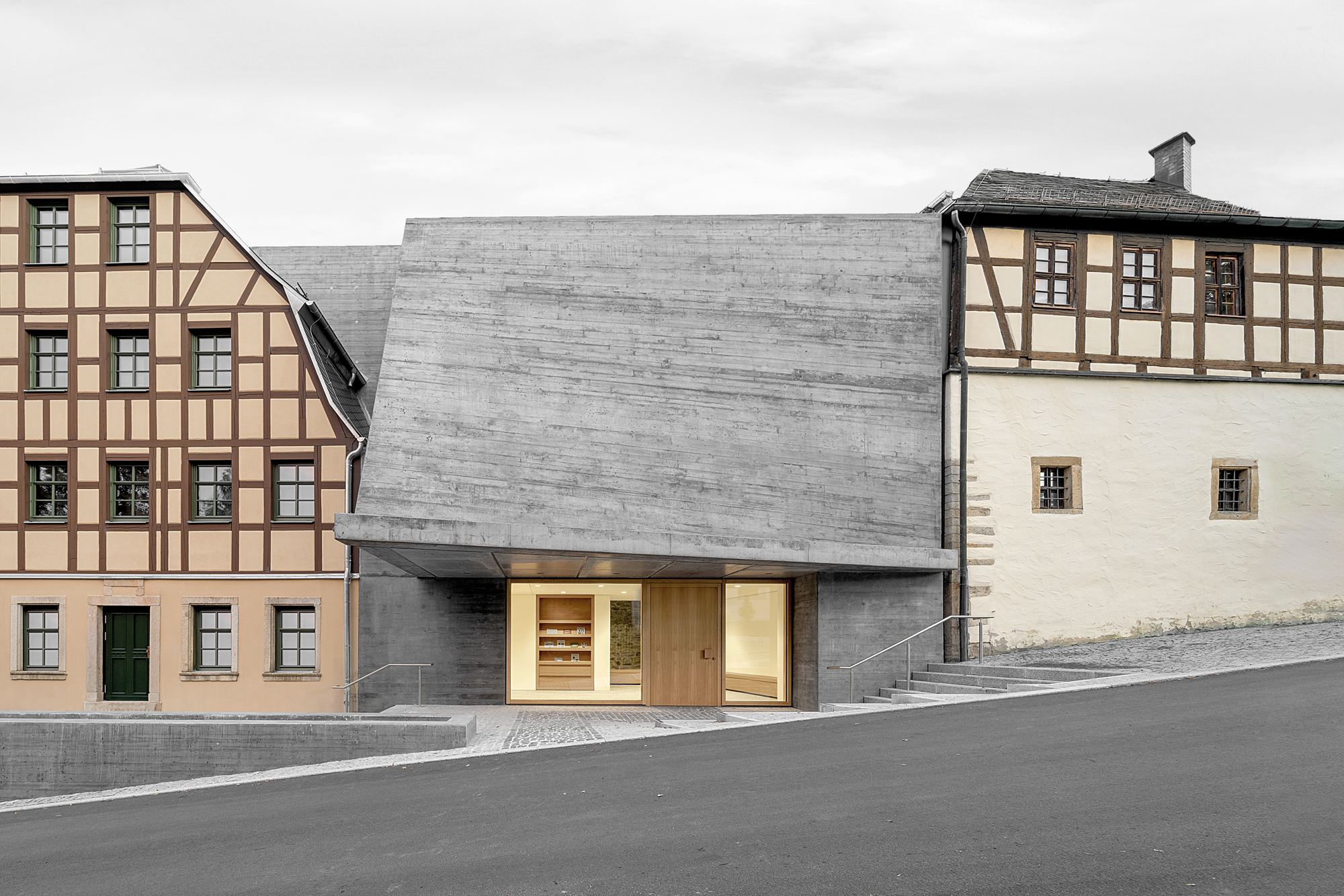 Das neue Eingangs­gebäude verbindet zwei historische Fachwerkhäuser. Die eigenwillige Geometrie der Hyparschale lässt sich im Schalungsbild ab­lesen.