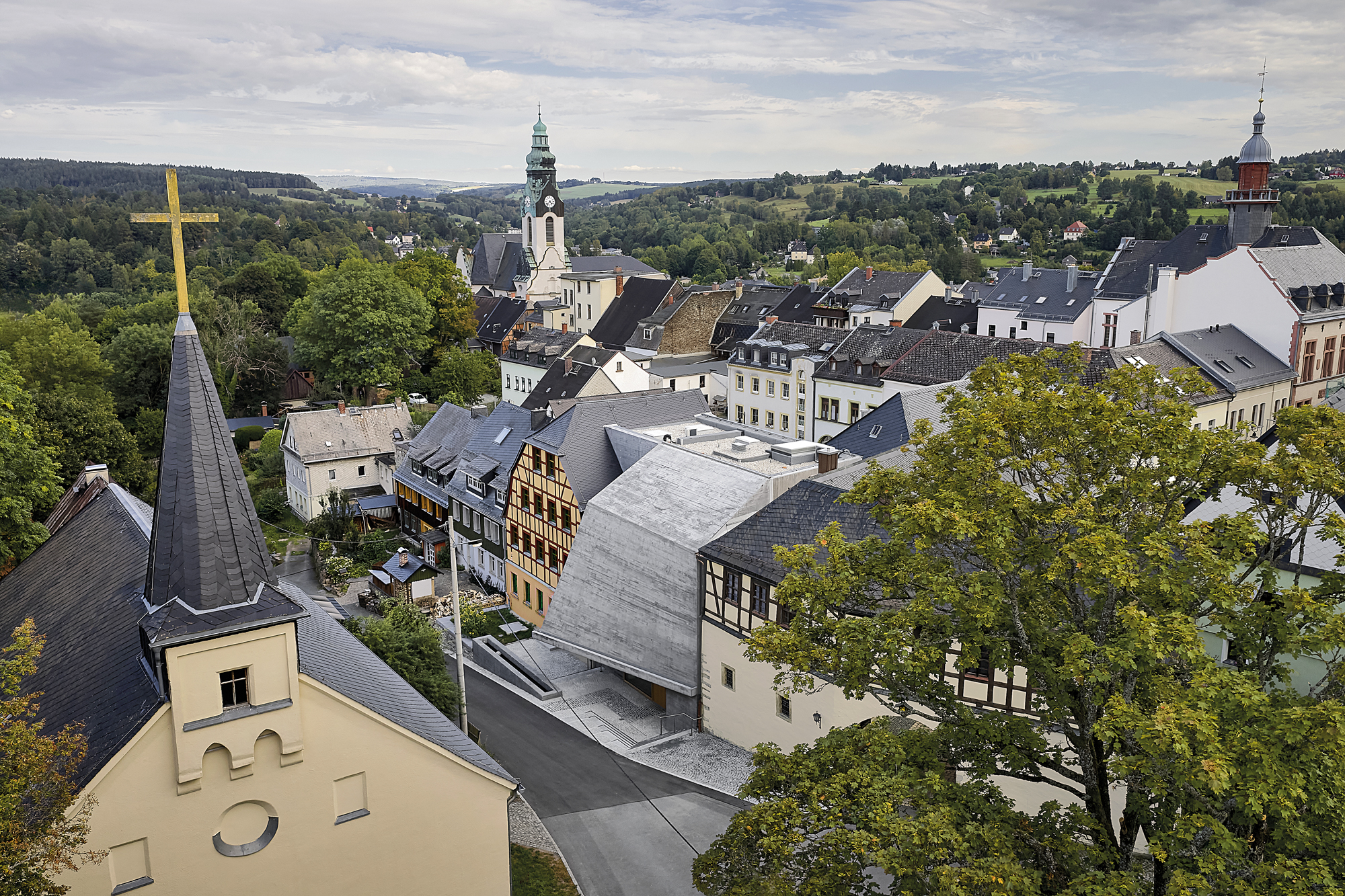 Durch die doppelt gekrümmte Fassadenfläche entsteht ein weit auskragendes Vordach. Es betont den Eingang und schafft eine großzügige Geste im Straßenraum.