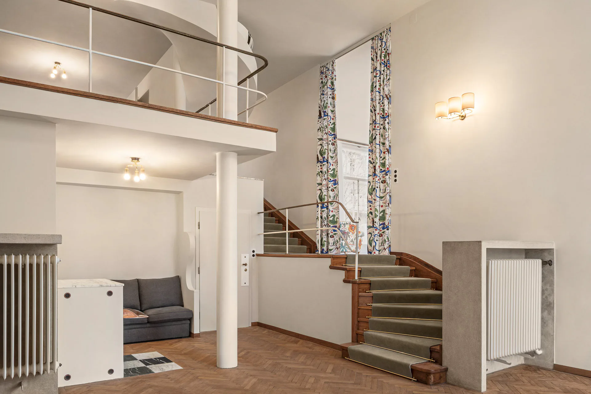 Ein Blick ins Innere der Villa Beer zeigt den restaurierten Boden, das Zwischengeschoss und die elegant geschwungene Treppe, die die originale Raumwirkung wiederherstellen.