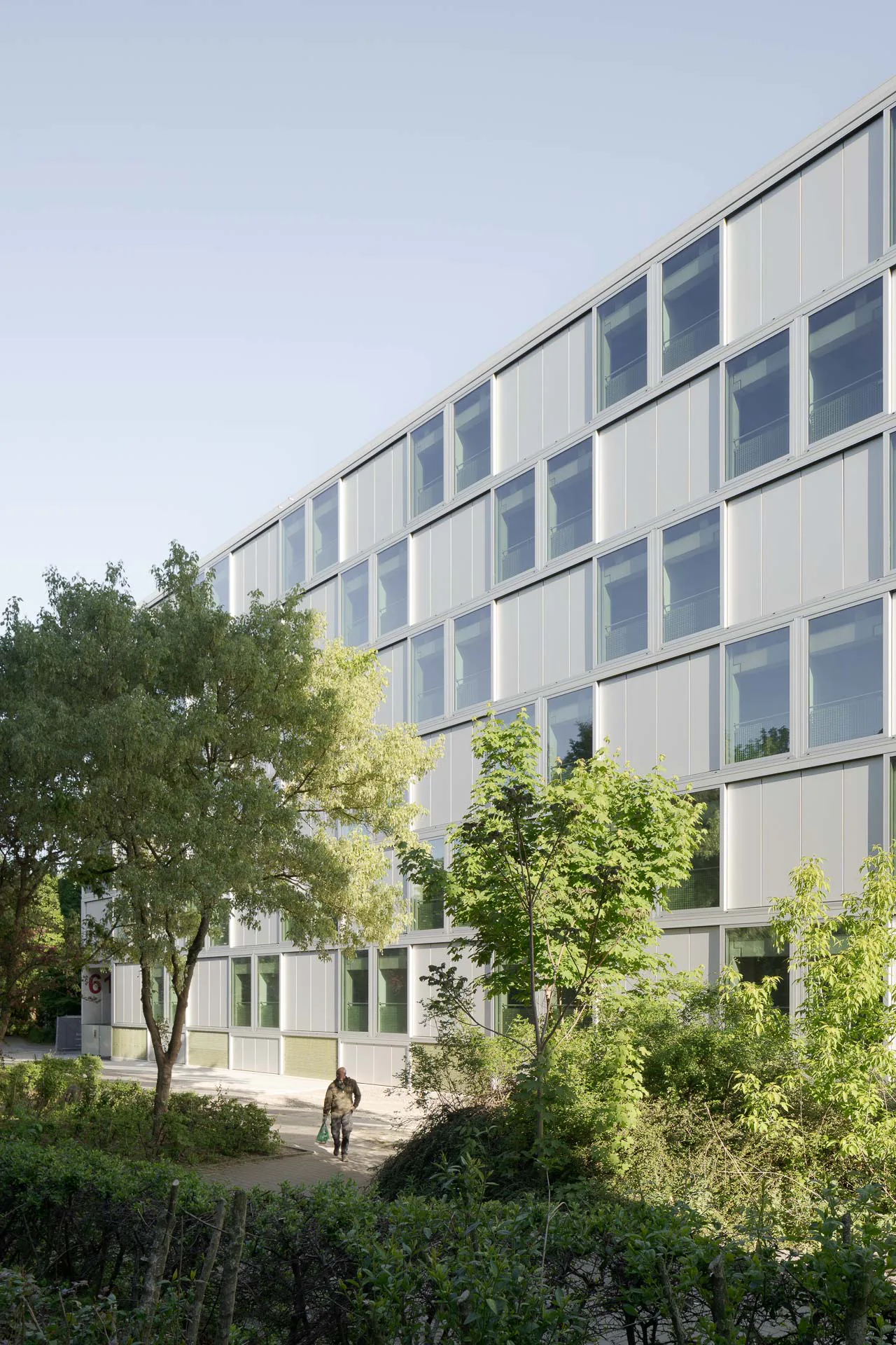 Die Straßenfassade wird von einem Schachbrettmuster aus geschlossenen und verglasten Flächen gegliedert.