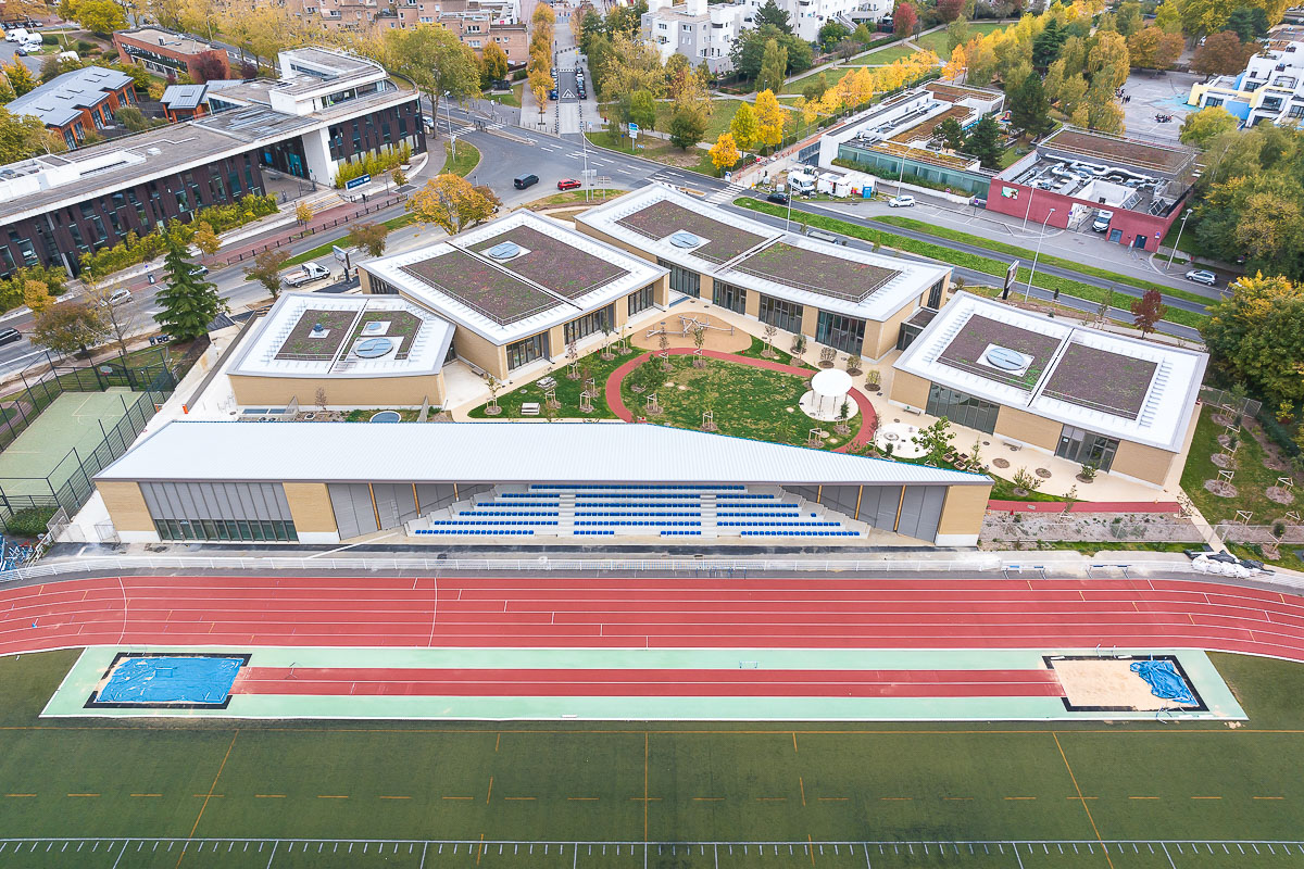 Der Gebäudekomplex des Kinder- und Sportzentrum von HEMAA Architectes fügt sich harmonisch in die umgebende Topografie und Landschaft ein.