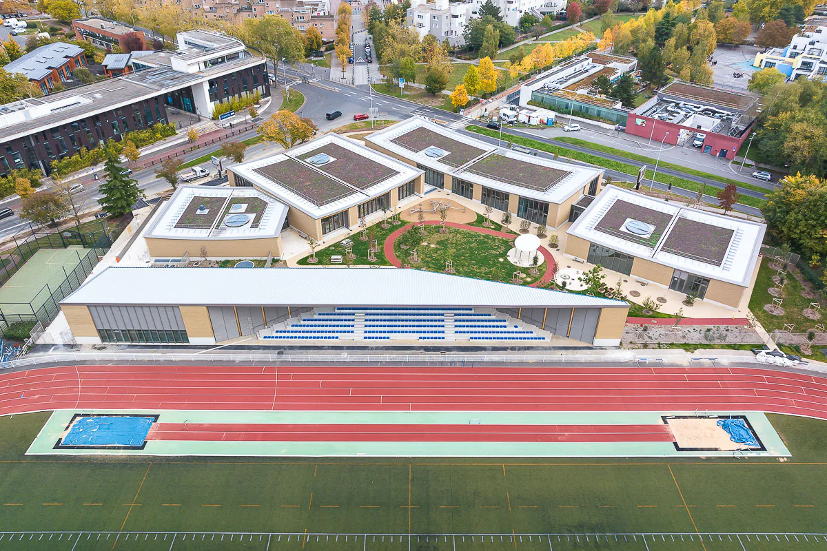 Der Gebäudekomplex des Kinder- und Sportzentrum von HEMAA Architectes fügt sich harmonisch in die umgebende Topografie und Landschaft ein.