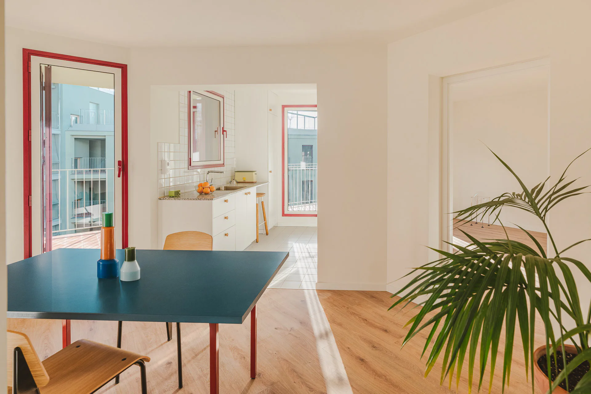 Die roten Fensterrahmen bilden auch im Inneren der Wohnung einen Farbtupfer. Durch die aus der Achse gedrehte Anordnung der Küchen fällt der Blick nach zwei Richtungen ins Freie.