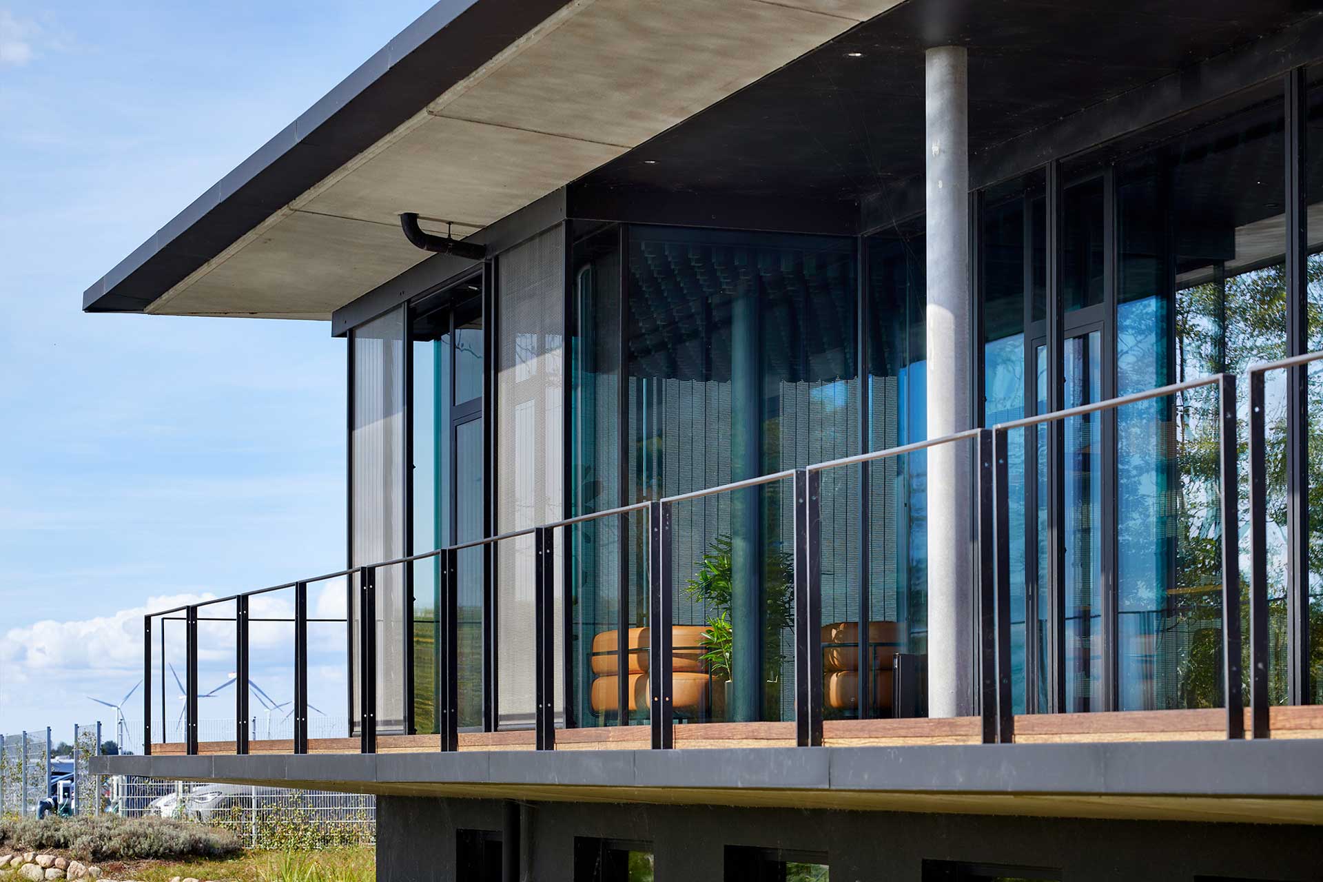 Durch den umlaufenden Balkon sind der Innen- und Außenraum miteinander verbunden. Die filigranen Linien unterstreichen die leichte, transparente Architektursprache des Gebäudes.