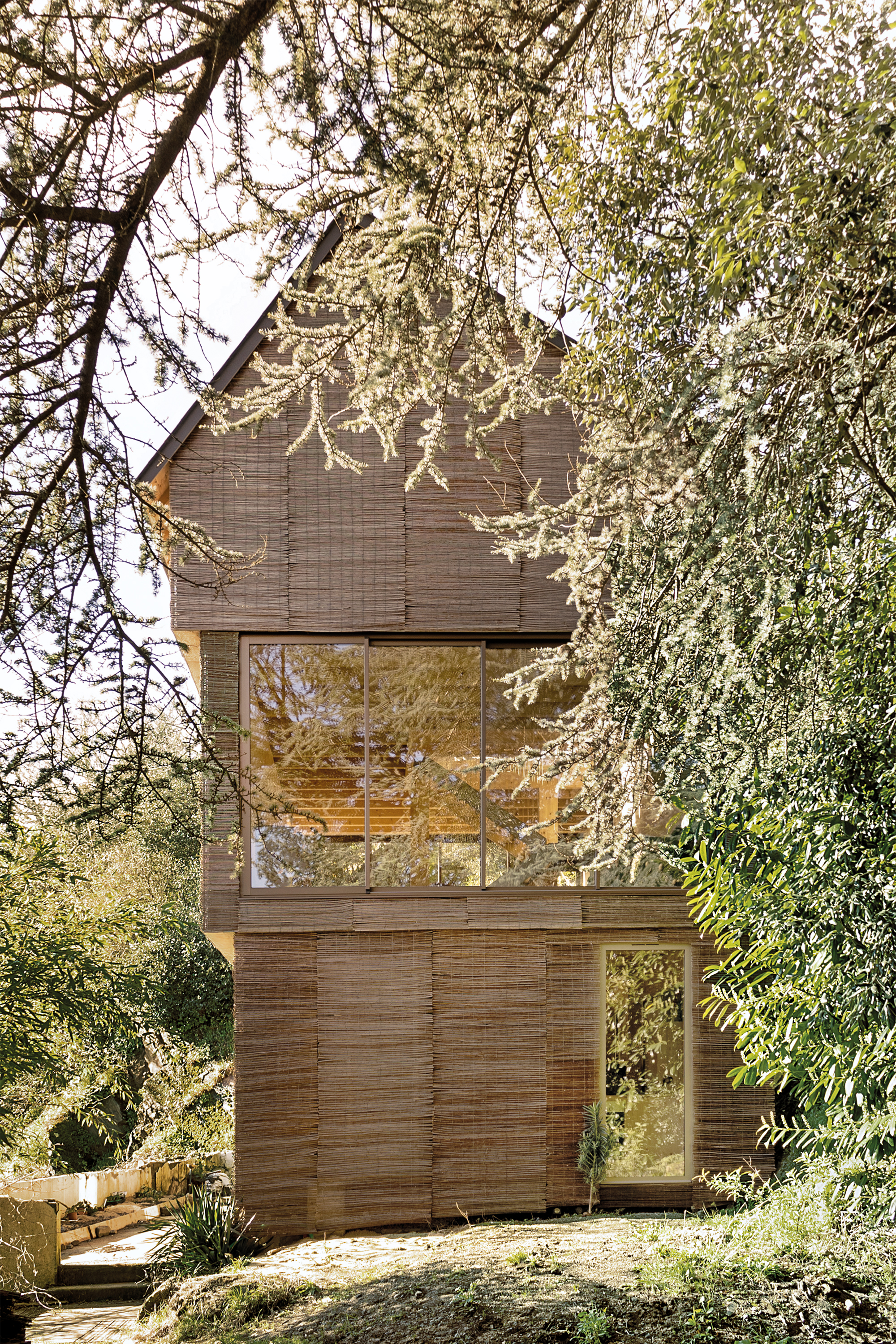 The wickerwork mats allow the Toue Cabanée to merge with its natural surroundings. The large window openings of the two gable facades permit a view through the interior to the other side.