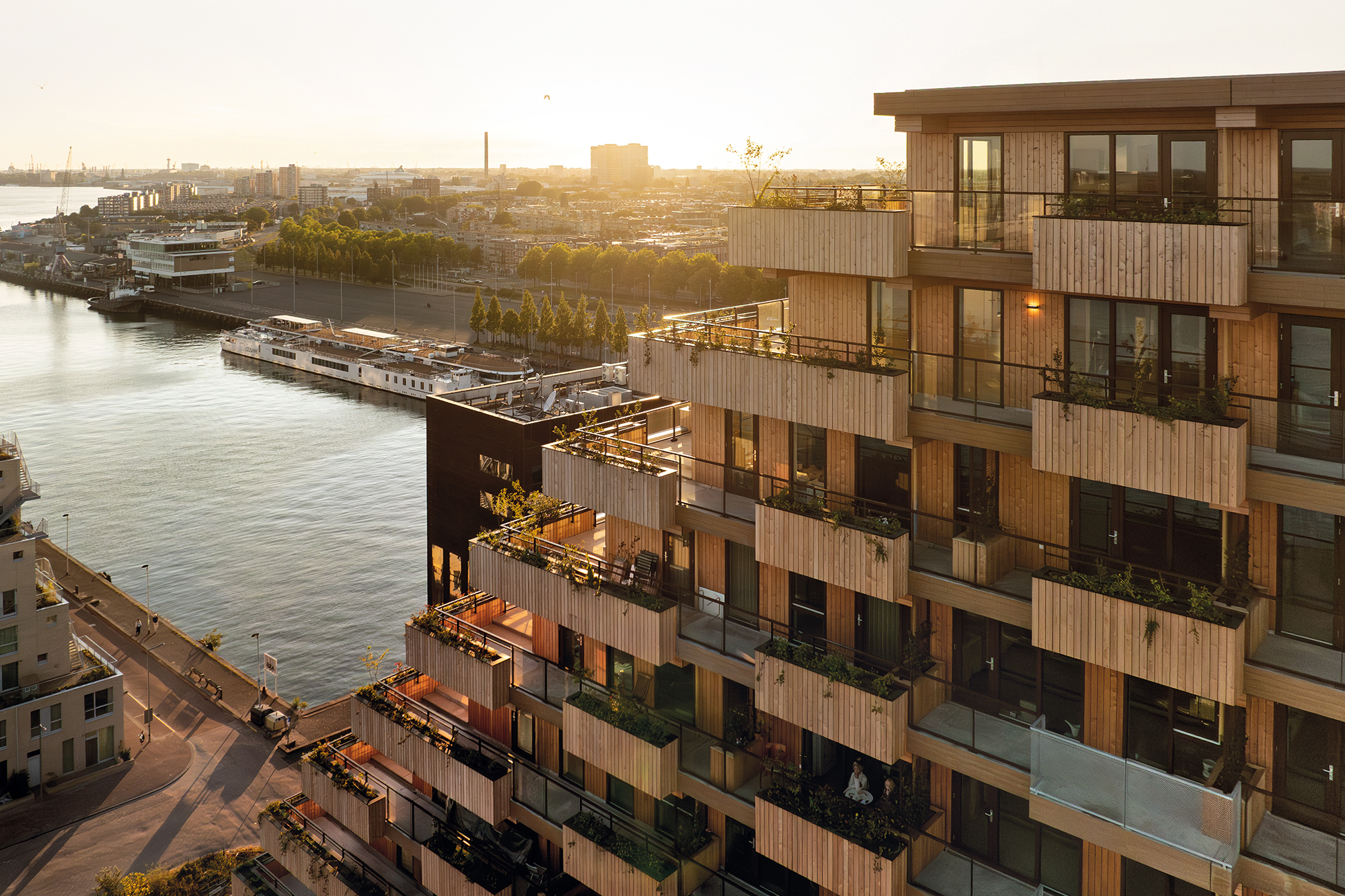 In Richtung Westen ist der Baukörper mit großzügigen Terrassen abgetreppt. An den Nord- und Südfassaden wechseln sich Balkone mit Holz- und Glasgeländern ab.