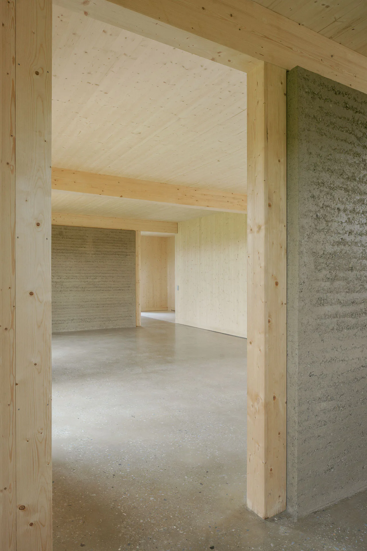 Brettsperrholz-Elemente und Böden aus Stampflehm lassen eine helle und ruhige Atmosphäre entstehen und strahlen Wärme aus.