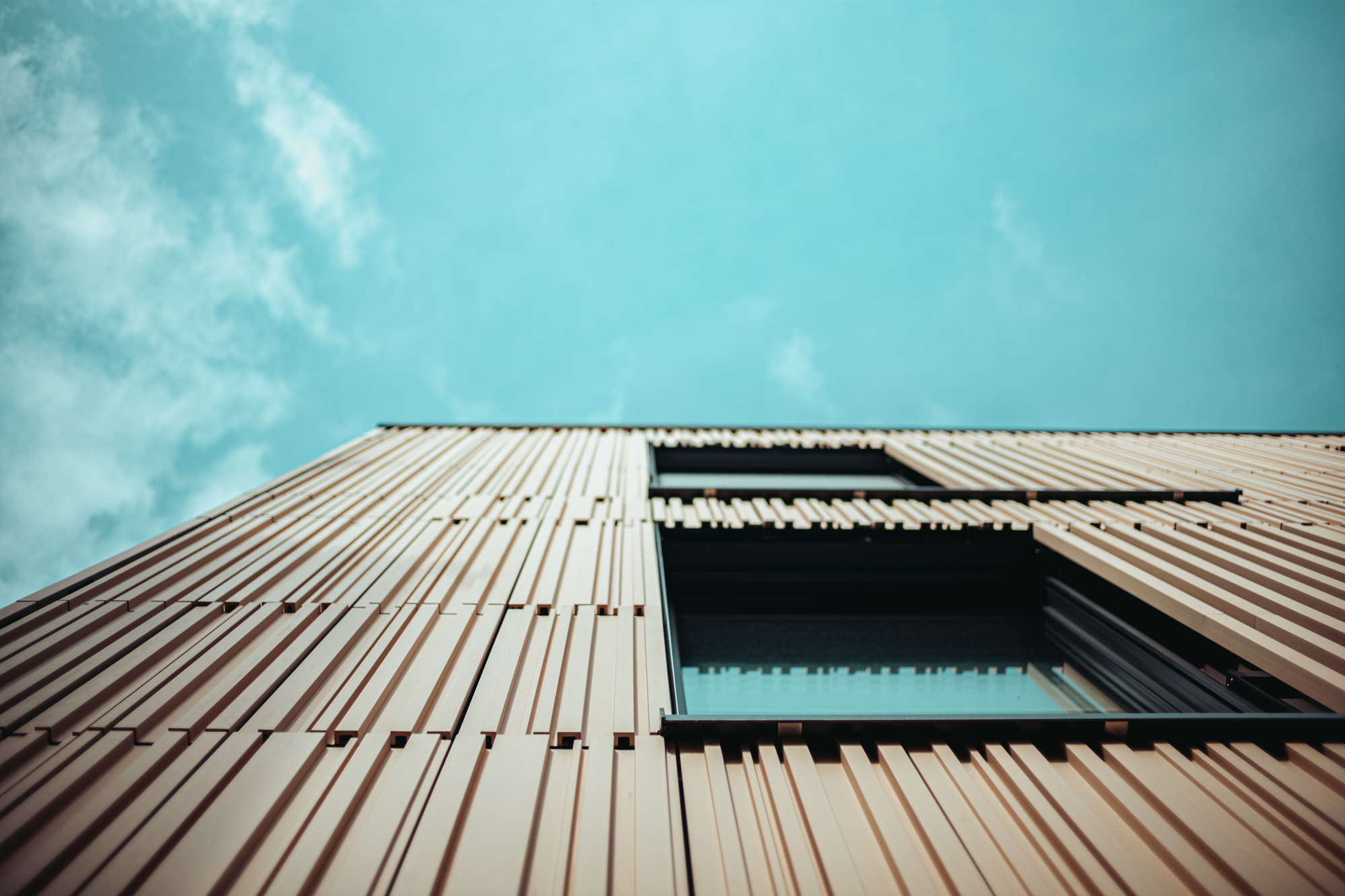 The relief texture of the ceramic panels creates vivid light and shadow effects, accentuating the facade’s vertical rhythm.