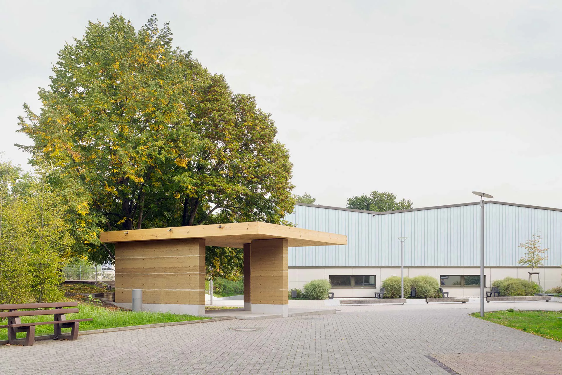 Öffentlich zugänglich, auf dem Schulhof zeigt das kleine Gebäude den Vorbeigehenden wie zeitgemäßes Bauen mit Stampflehm aussehen kann.