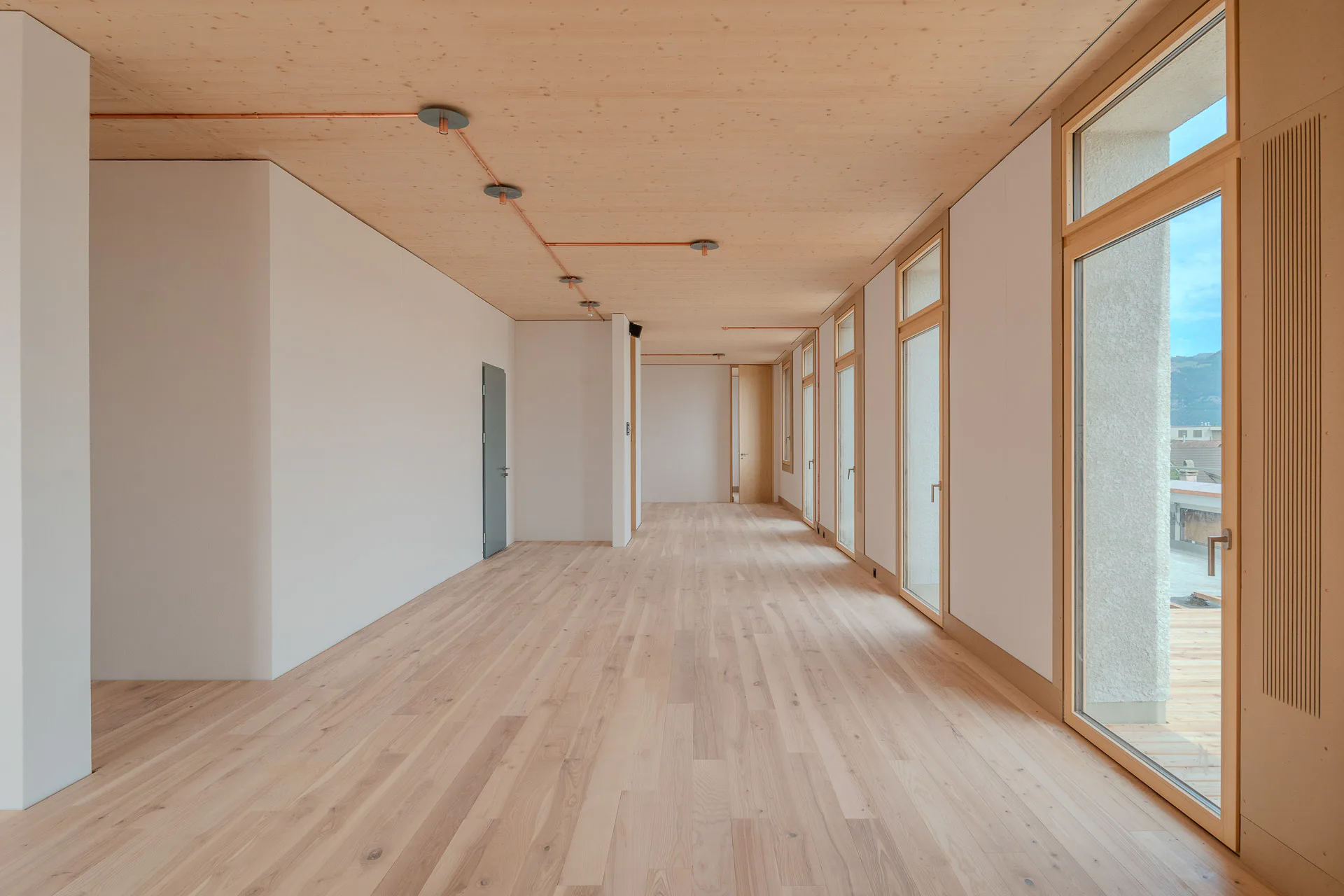 The wooden ceilings are exposed on every floor. The cross-laminated timber elements are supported by reused steel beams.