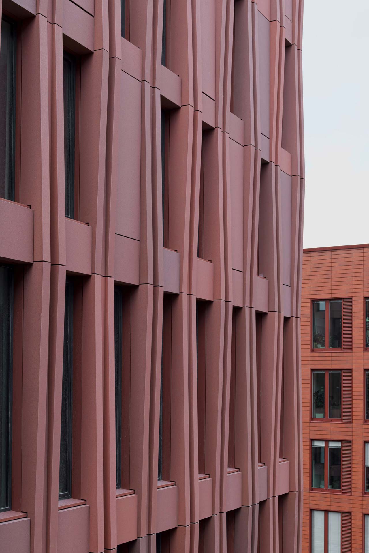 Präzise formparts aus Glasfaserbeton strukturieren die Fassade und erzeugen ein klares Spiel aus Rhythmus und Proportion.