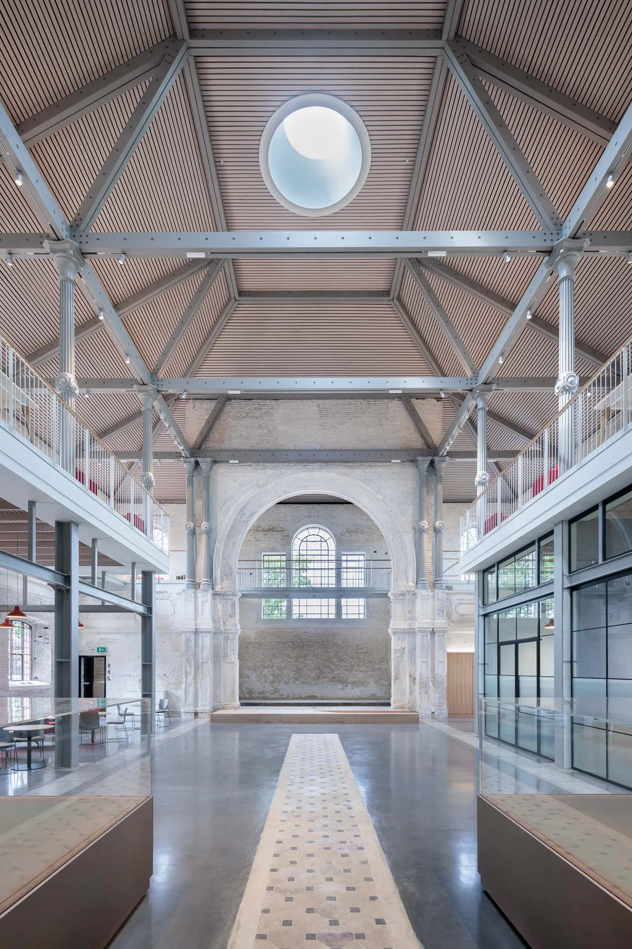 Originalsteinfliesen in Form eines länglichen Streifens sind in den polierten Betonboden eingearbeitet. Die neue Dachkonstruktion überspannt das Kirchenschiff.