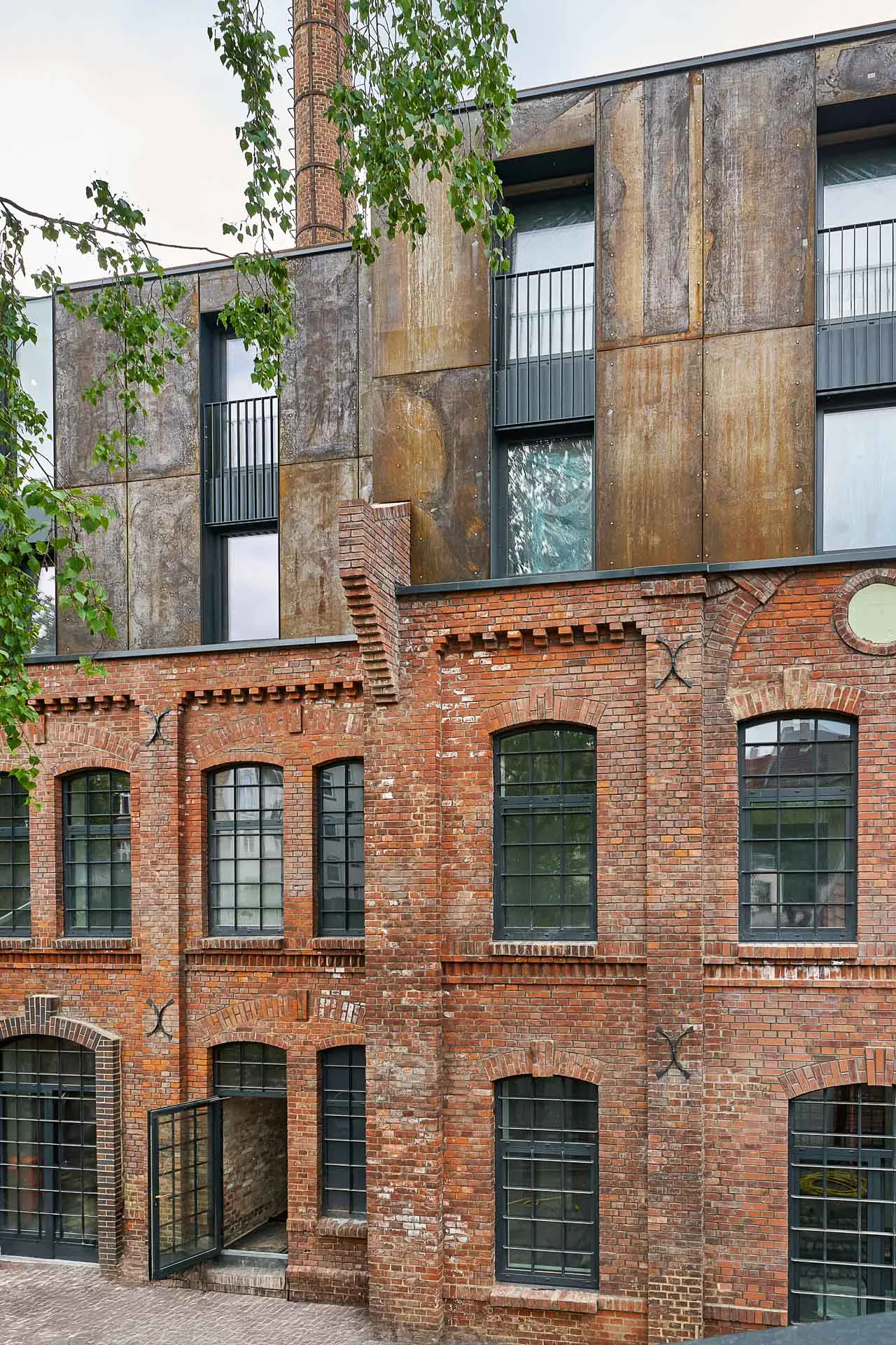 Eine vorgehängte hinterlüftete Cortenstahl-Fassade bildet das zeitgenössische Pendant zum roten Ziegel.