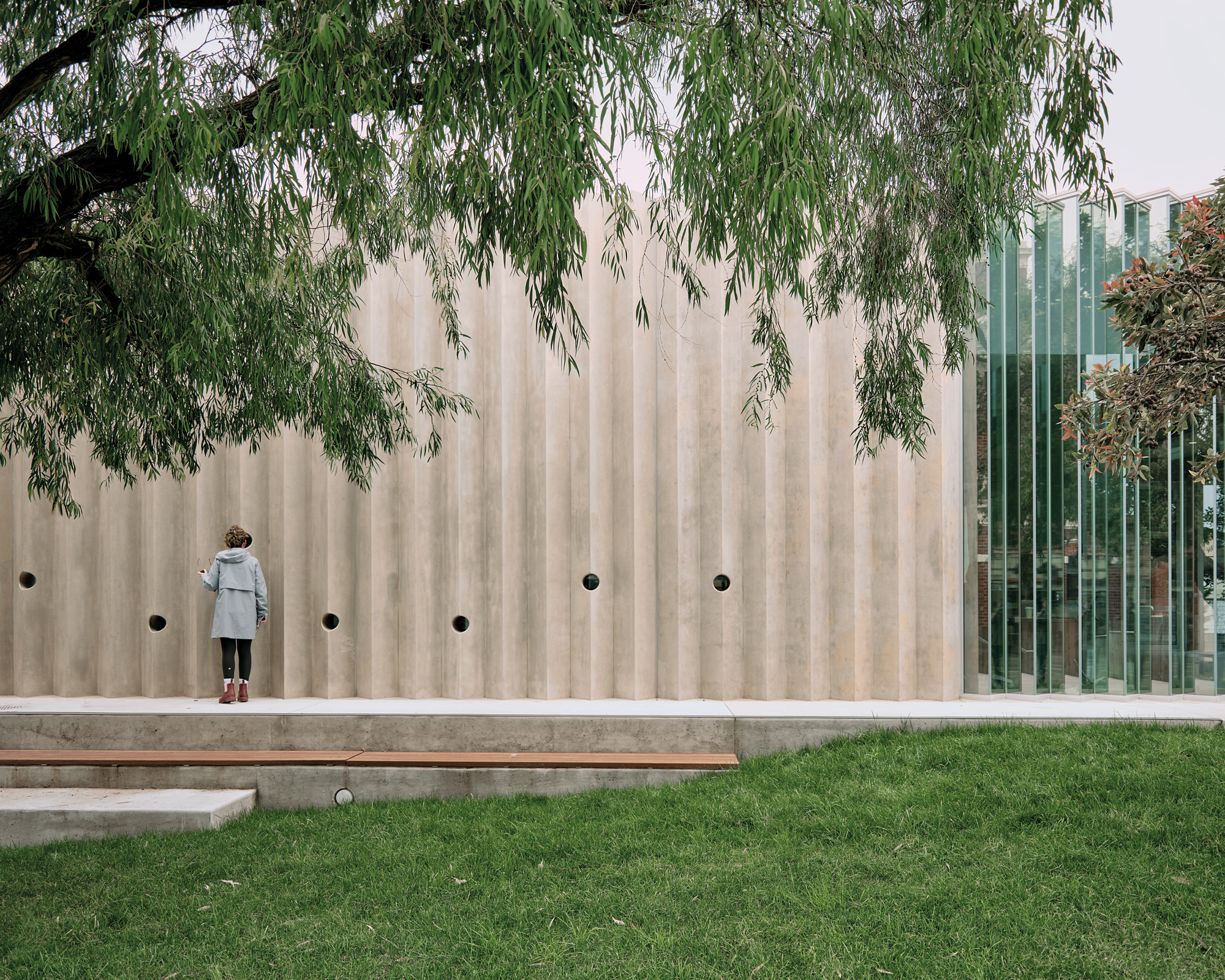 Kreisrunde Guckfenster in der Betonwand erlauben Einblicke in das Gemeindezen-trum, das Kerstin Thompson Architects 2024 in der südaustralischen Küstenstadt Queenscliff fertigggestellt haben.