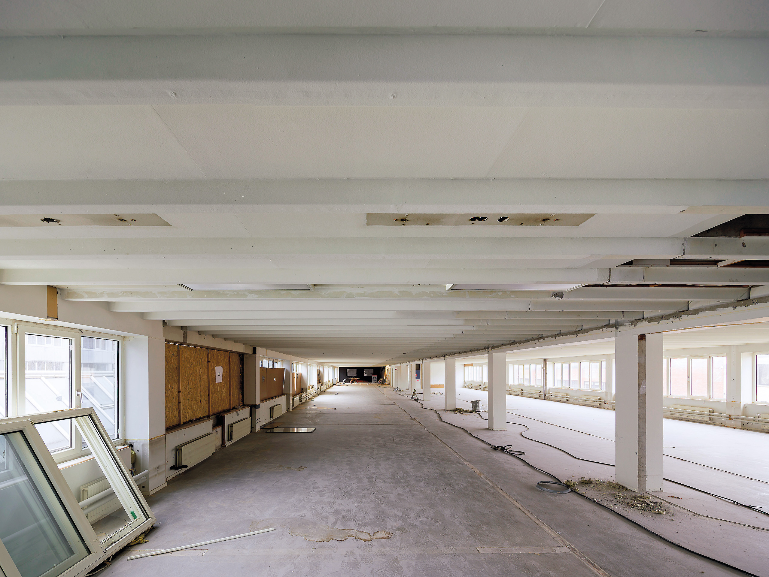 The administrative building was previously organized horizontally, with low ceiling heights, a strict grid, and long strip windows.