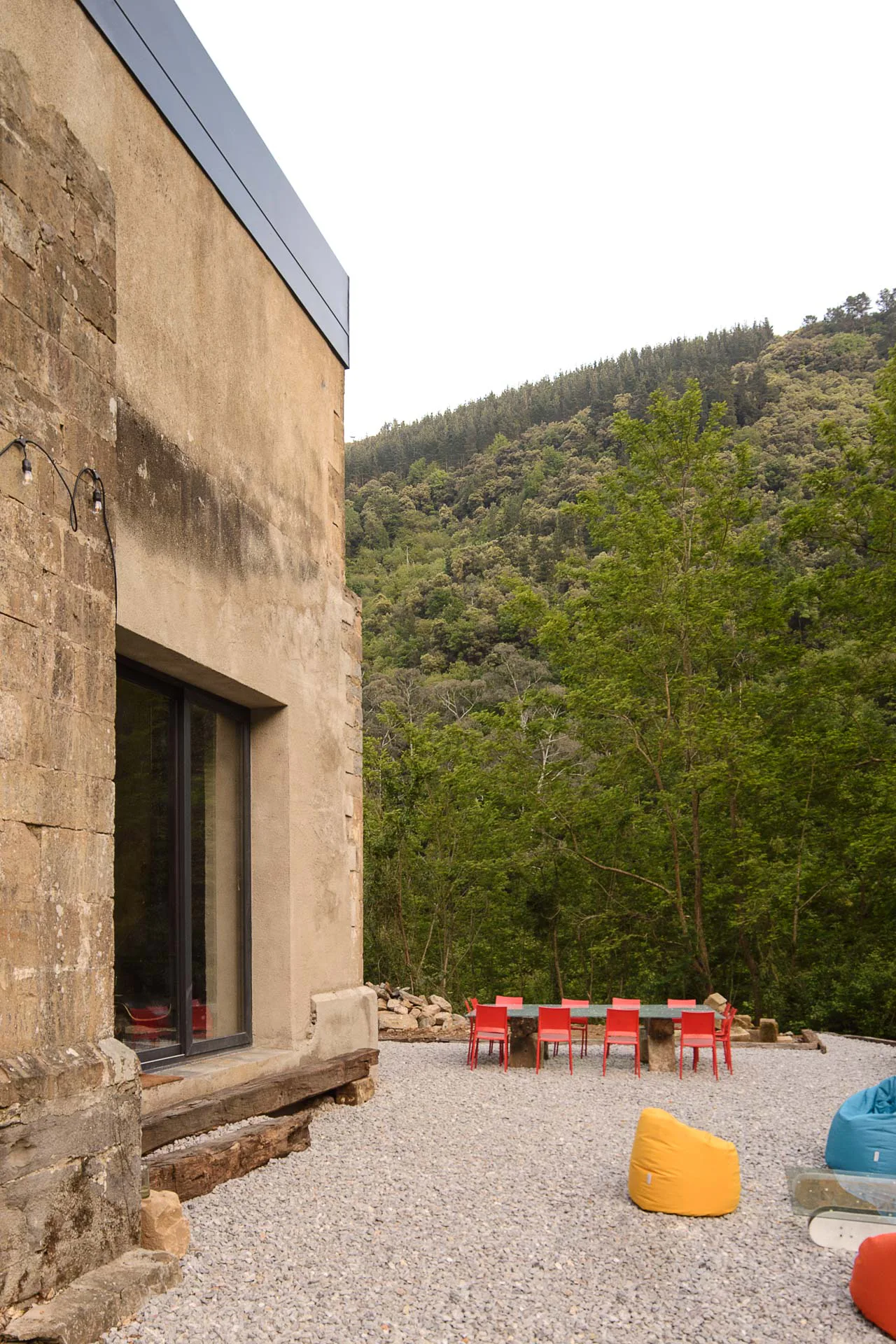 Eine großzügige Terrasse umgibt die transformierte Kapelle und bietet einen Blick in die üppige Vegetation des Waldgeländes.