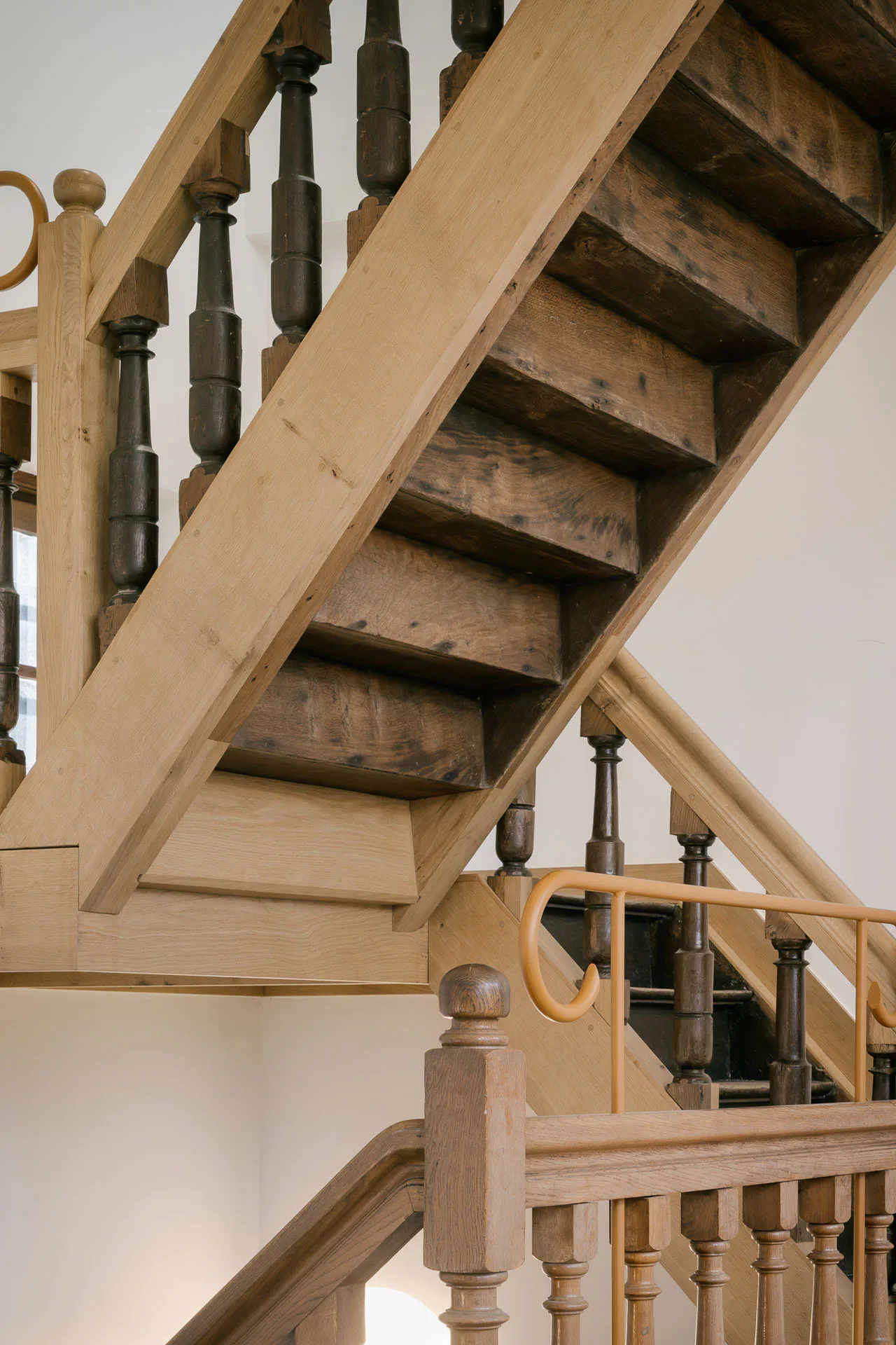 Vier alte Treppen und zahlreiche frische Eichenbalken wurden zu einer neuen zusammengefügt. Metallgeländer gewährleisten die notwendige Absturzsicherung.