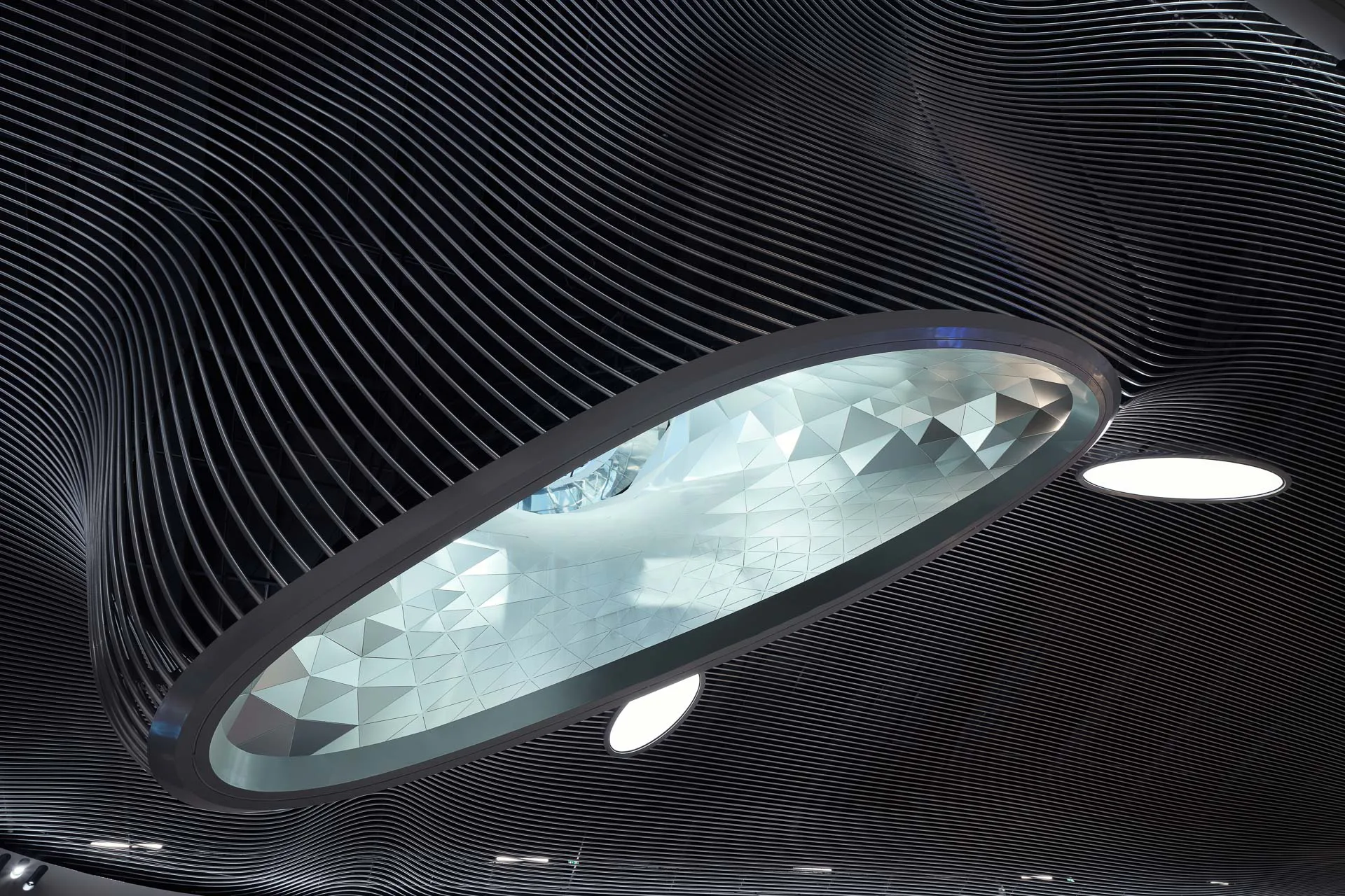 Zusätzlich zu den Lichttrichtern sind runde Beleuchtungskörper in die Röhrendecke integriert.