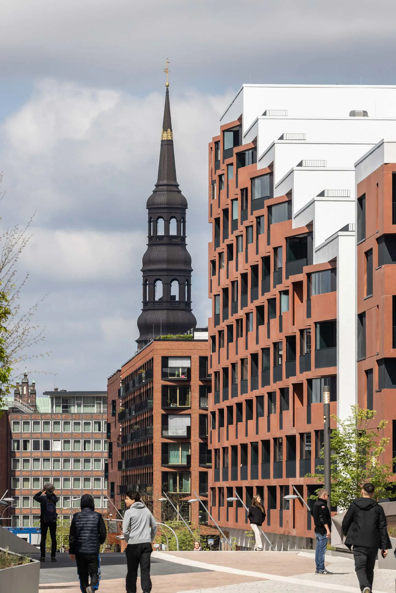 Der plastisch gegliederte Baukörper reagiert mit abgetreppten Terrassen und roter Sichtbetonfassade auf die dichte städtebauliche Struktur der HafenCity.