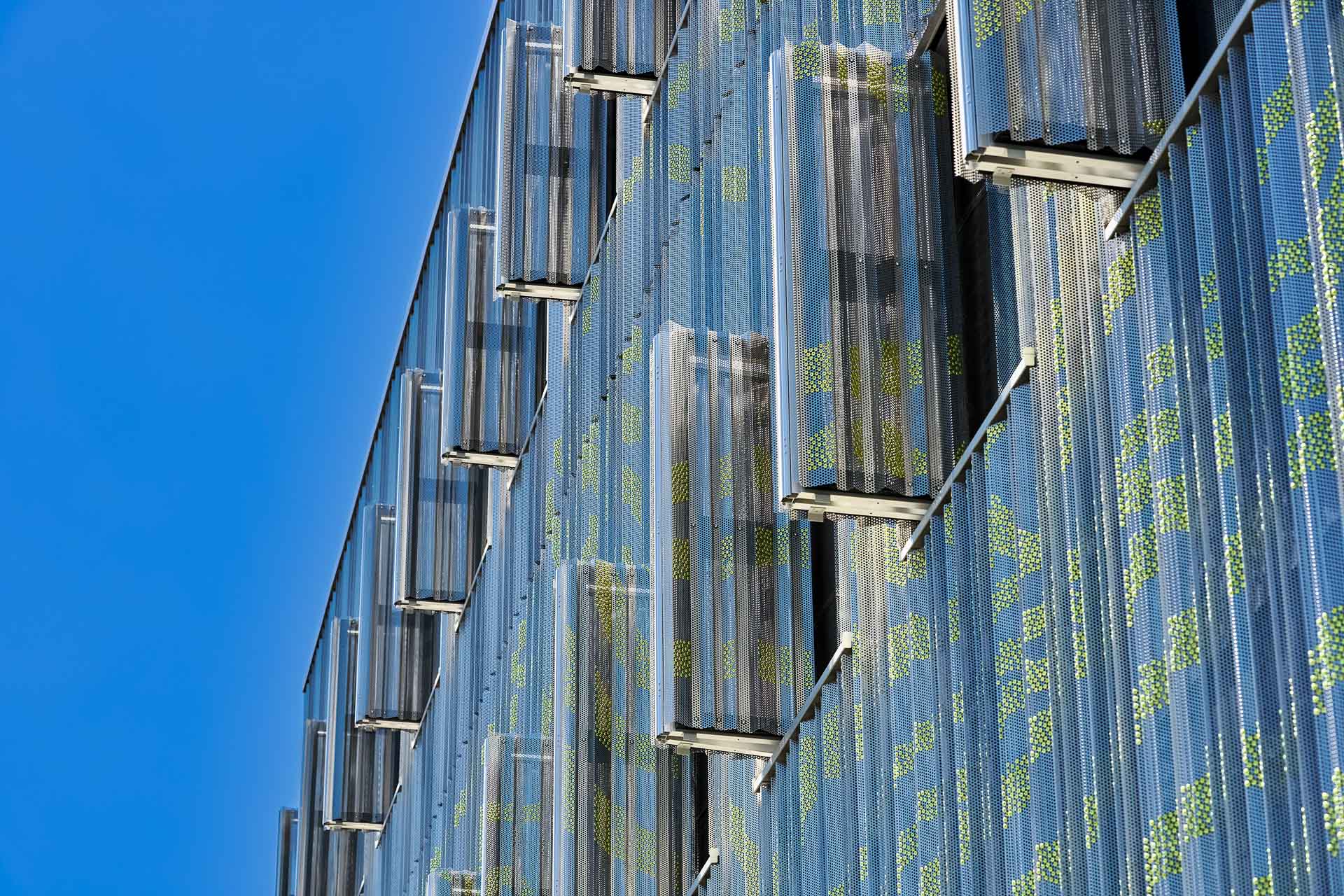 Hinter der Fassade aus gekanteten und gefalteten Lochblechen verbirgt sich unter anderem ein Depot, dessen Bestände unter anderem durch außenliegenden Sonnenschutz vor UV-Strahlung und Wärme geschützt werden.