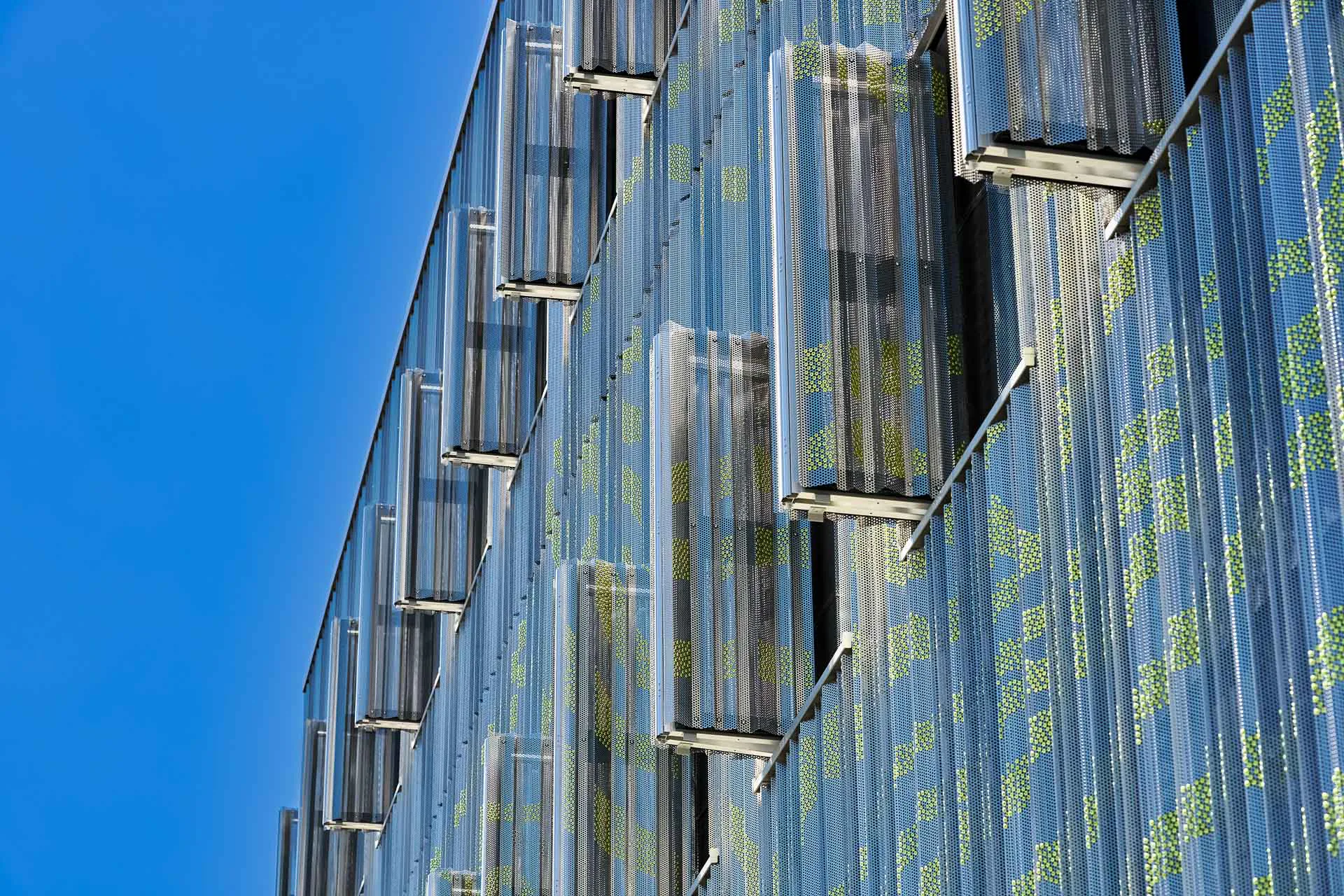 Hinter der Fassade aus gekanteten und gefalteten Lochblechen verbirgt sich unter anderem ein Depot, dessen Bestände unter anderem durch außenliegenden Sonnenschutz vor UV-Strahlung und Wärme geschützt werden.